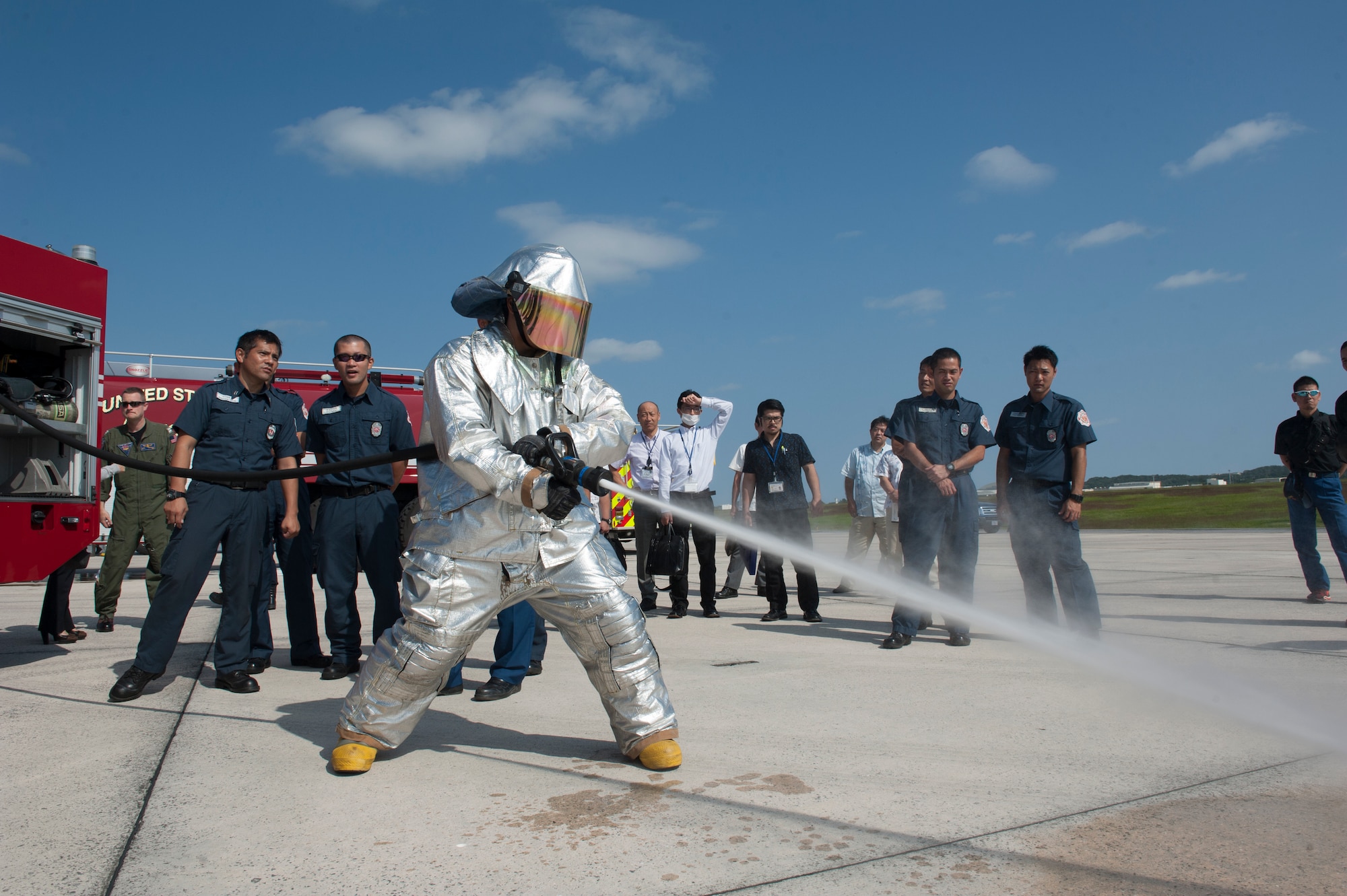 Hideo Shinya, 18th Civil Engineer Squadron firefighter, demonstrates the power of a fire hose during a bilateral aircraft egress training event Oct. 29, 2015, at Kadena Air Base, Japan. Members from the 18th CES showed local Okinawan emergency responders the vehicles they could possibly see respond to an aircraft mishap and the tools that could be used to contain an incident if it were to happen. (U.S. Air Force photo by Airman 1st Class Lynette M. Rolen)