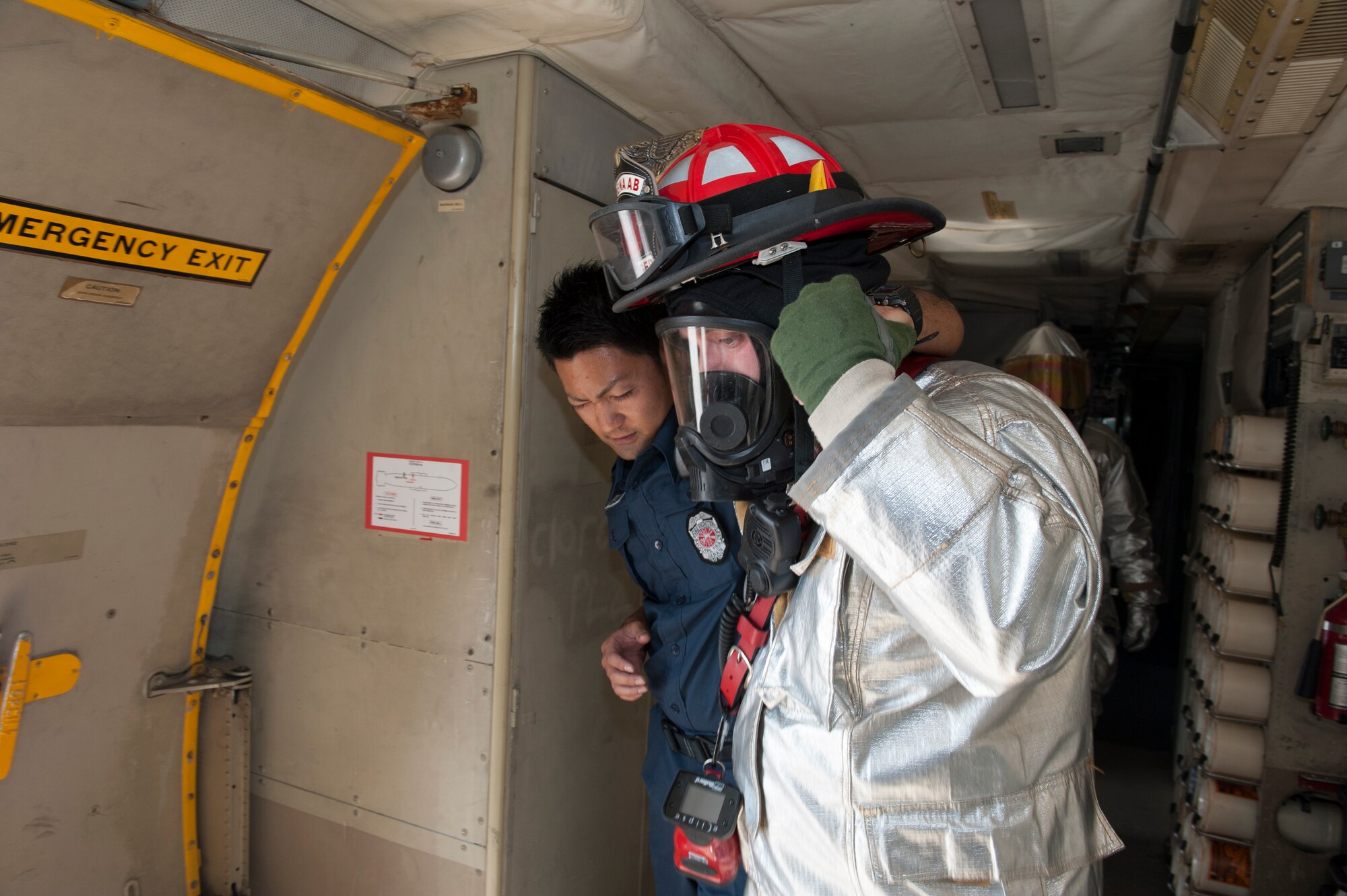 U.S. Air Force Staff Sgt. Craig Hassinger, 18th Civil Engineer Squadron crew chief, performs an egress training demonstration with a local Okinawan firefighter as part of the P-3 bilateral training Oct. 29, 2015, at Kadena Air Base, Japan. The purpose of this training was to show local emergency responders what they can do in the event of an aircraft mishap off-base. The egress involved demonstrating the rescue of any injured flight personnel from an aircraft. (U.S. Air Force photo by Airman 1st Class Lynette M. Rolen)