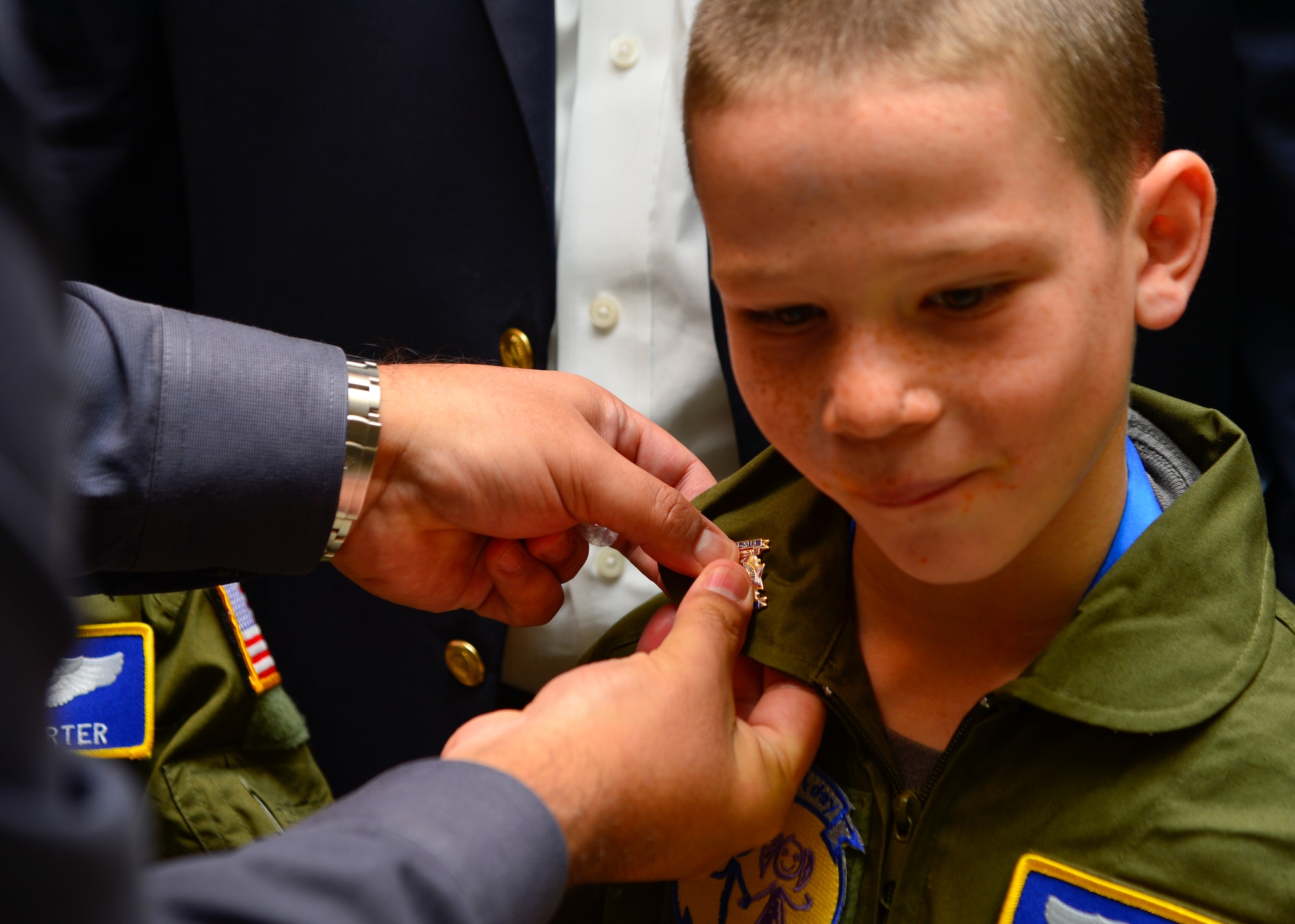 Marc Garduno, Veterans of Foreign Wars Post #3238 commander, pins on a VFW pin onto Blake Boyer’s flight suit during the Pilot for the Day program Oct. 26, 2015, at Dover Air Force Base, Del. The VFW Post #3238 donated $200 towards the program that helped purchase the flight suits and certificate frames that were given to Blake and Ben Carter. (U.S. Air Force photo/Senior Airman William Johnson)