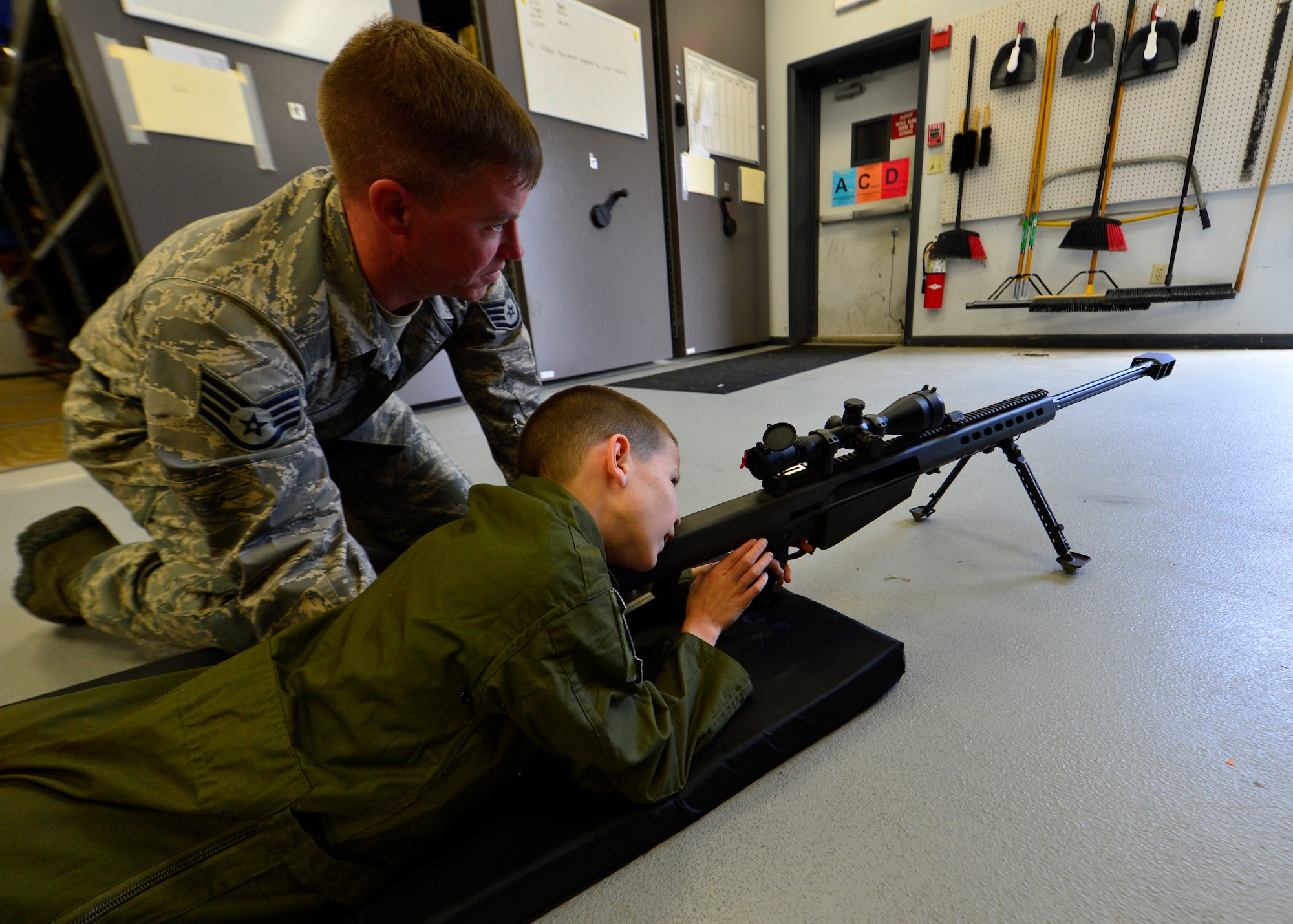 Staff Sgt. John Nelson, 512th Civil Engineer Squadron explosive ordnance disposal technician, shows Blake Boyer a non-functional Barrett .50 Cal sniper rifle during his visit to the EOD facility during the Pilot for a Day program Oct. 26, 2015, at Dover Air force Base, Del. Boyer was shown various weapon systems and local ordnance recovered by EOD during his visit to their facility. (U.S. Air Force photo/Senior Airman William Johnson) 