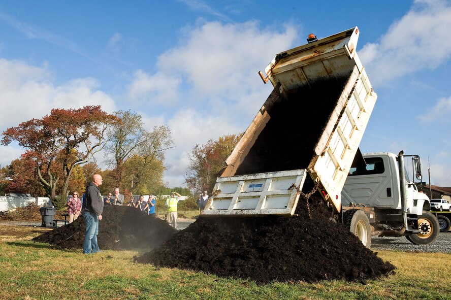 Michael Farkas, 436th Civil Engineer Squadron housing manager, watches Antonio Bray, City of Dover streets field supervisor, dump leaf mulch at the new organic community garden Oct. 29, 2015, on Dover Air Force Base, Del. The City of Dover, one of many Air Force Community Partnership Program P4 initiative stakeholders in the community garden initiative at Dover AFB, donated and delivered three dump truck-loads of leaf mulch that was tilled into the soil. (U.S. Air Force photo/Roland Balik)