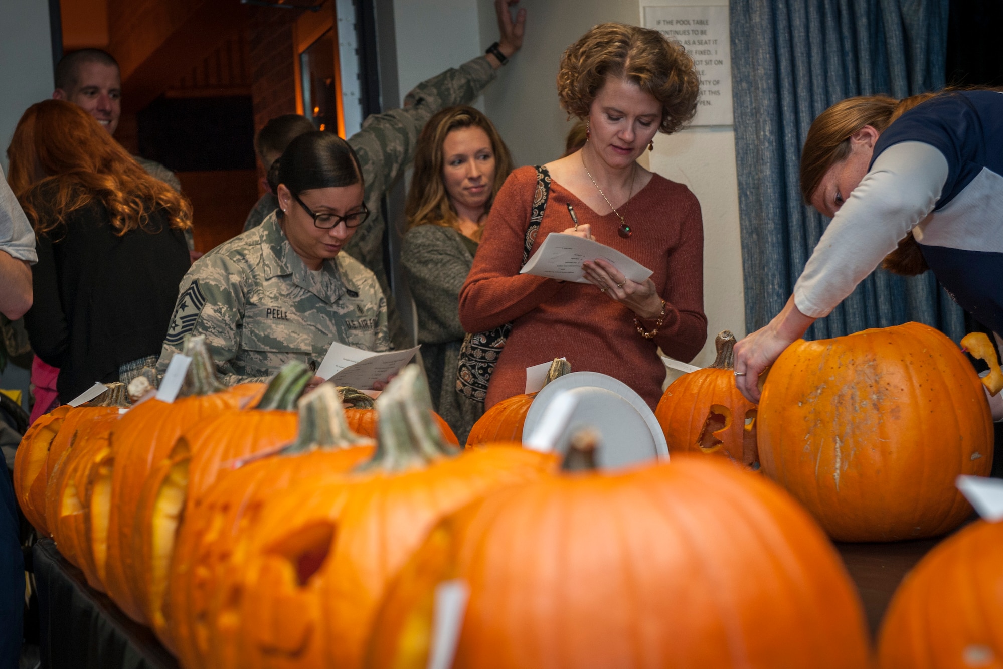 PETERSON AIR FORCE BASE, Colo. -- Judges for the Peterson Chapel's 3rd Annual Pumpkin Carving Contest deliberate over the 15 submissions at Patriot Hall, Oct. 28, 2015. Pumpkins and carving tools were provided by the chapel and the event encouraged wholesome holiday fun. (U.S. Air Force photo by Senior Airman Rose Gudex)