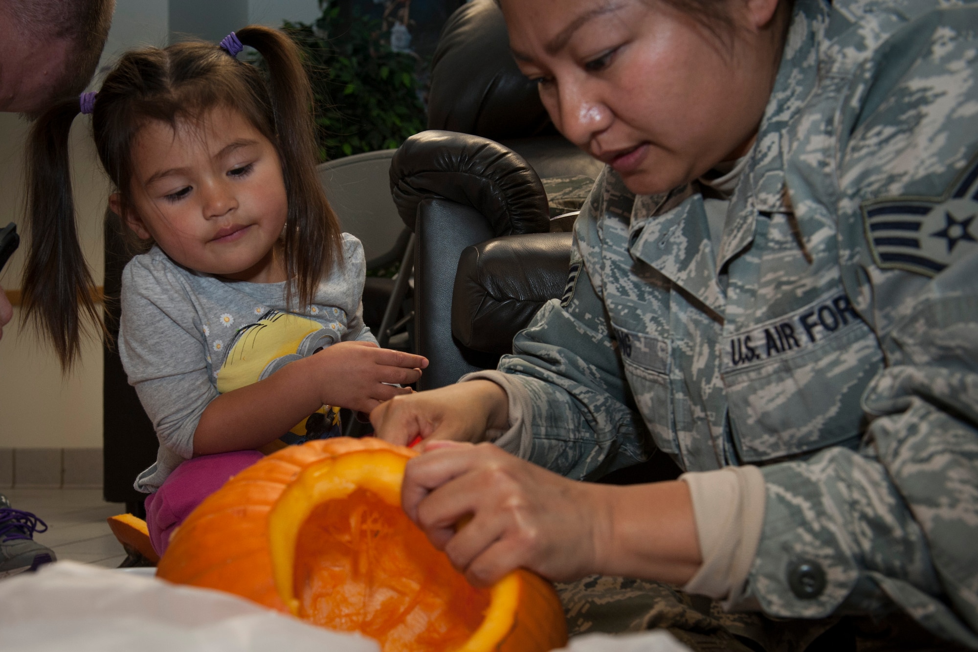 PETERSON AIR FORCE BASE, Colo. -- Marie Long, 2, watches her mom, Staff Sgt. Riza Long, carve a pumpkin before helping at the Peterson Chapel's 3rd Annual Pumpkin Carving Contest, Oct. 28, 2015. The event was held at Patriot Hall and all supplies were provided by the chapel. The event encouraged camaraderie and was a time for families to enjoy the Halloween spirit. (U.S. Air Force photo by Senior Airman Rose Gudex)