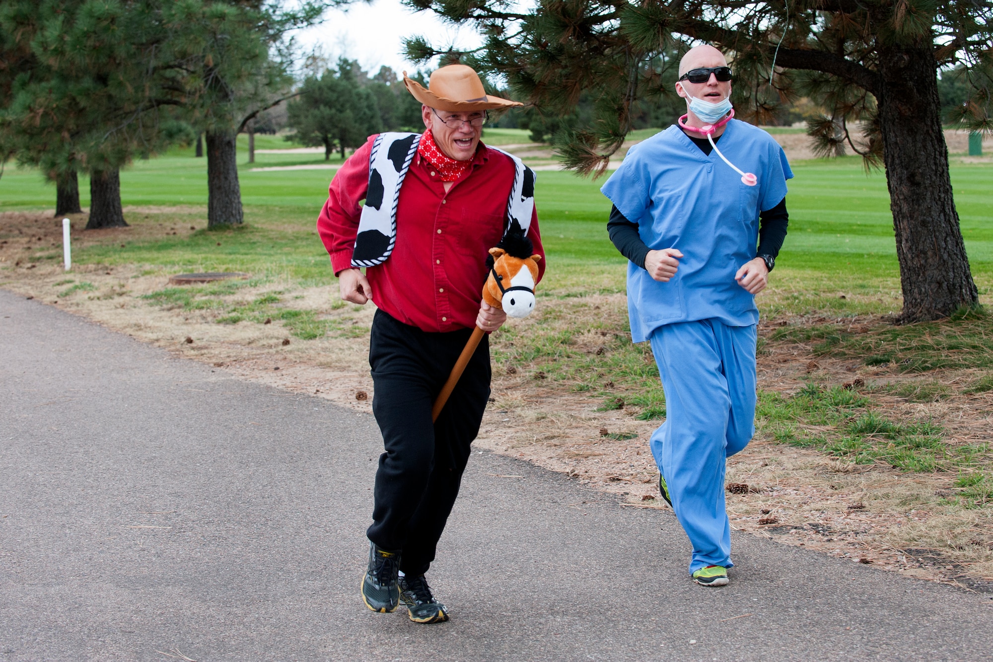 PETERSON AIR FORCE BASE, Colo. - Col. Reginald Ash (left), 21st Mission Support Group commander, and 1st Lt. Luke McIlroy, 21st Mission Support Group executive officer, participate in the 21st Space Wing Warfit fun run Oct. 30, 2015. Col. Ash made the run just a little easier by riding his pony around the 5K course. (U.S. Air Force photo by Craig Denton)