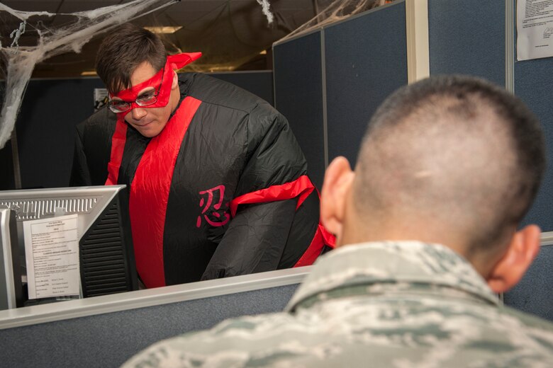 PETERSON AIR FORCE BASE, Colo. – Senior Airman Cameron Sizemore, 21st Comptroller Squadron military pay technician, helps a customer fill out some paperwork while in costume Oct. 30, 2015. The whole office was encouraged to wear costumes and went about their jobs as if it were any other normal day, including assisting customers. Costumes not only boosted their own morale, but the spirits of customers coming to the finance office. (U.S. Air Force photo by Senior Airman Rose Gudex)