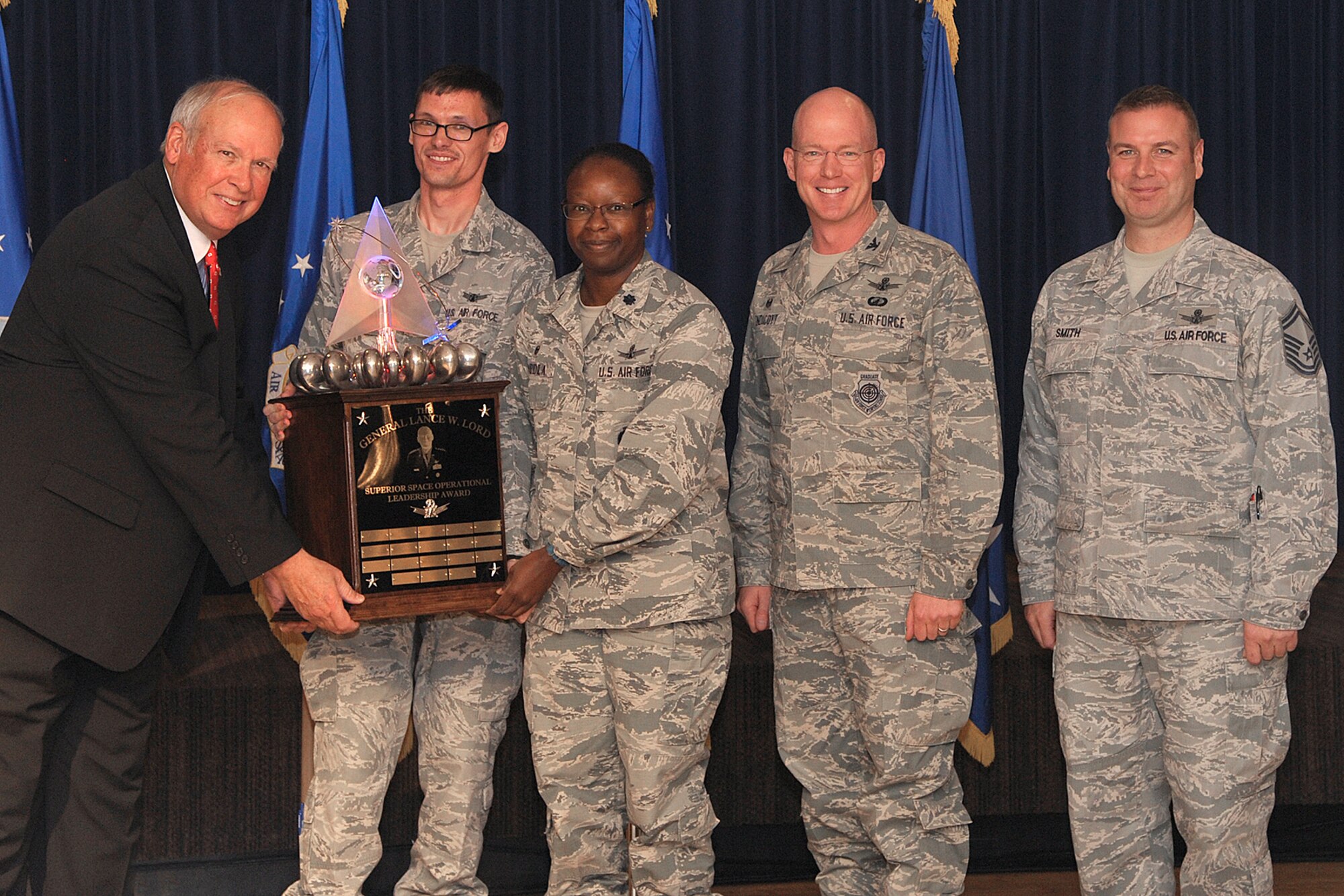 PETERSON AIR FORCE BASE, Colo. – Lt. Col. Mafwa Kuvibidila, 20th Space Control Squadron commander, center, received the General Lance W. Lord Award on behalf of her squadron for most outstanding unit in the 21st Operations Group. The 20th SPCS collected 11 million observations on earth-orbiting satellites, including debris, allied systems and adversary systems. They increased lost object detection by 200 percent by creating specialized radar search fences based on orbital predictions and founded a multi-national space situational awareness working group, which identified more than 30 cutting edge initiatives and optimized space operations for the joint fight. (U.S. Air Force photo by Duncan Wood)