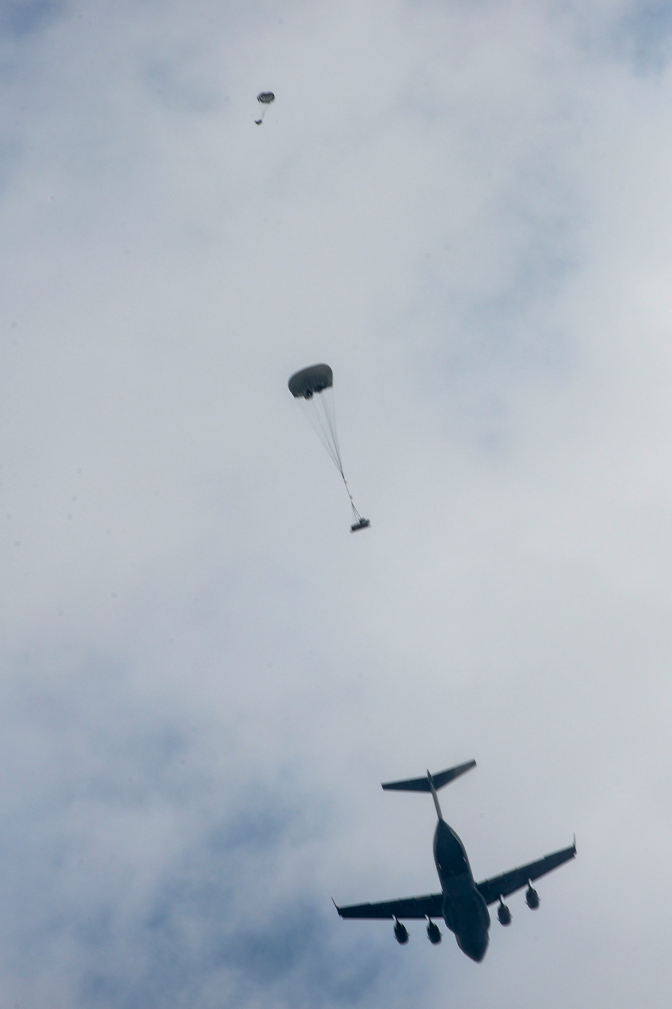 A C-17 Globemaster from Alaska Air National Guard’s 249th Airlift Squadron airdrops a Guardian Angel rescue team from Alaska ANG’s 212th Rescue Squadron and palletized rescue craft Oct. 31, 2015, near the coast of White Beach Naval Base, Japan. Members from the 212th RQS conducted long range search and rescue training, which entailed an approximately 12-hour flight to deliver rescue capabilities across the Pacific Ocean. (U.S. Air Force photo by Senior Airman John Linzmeier) 