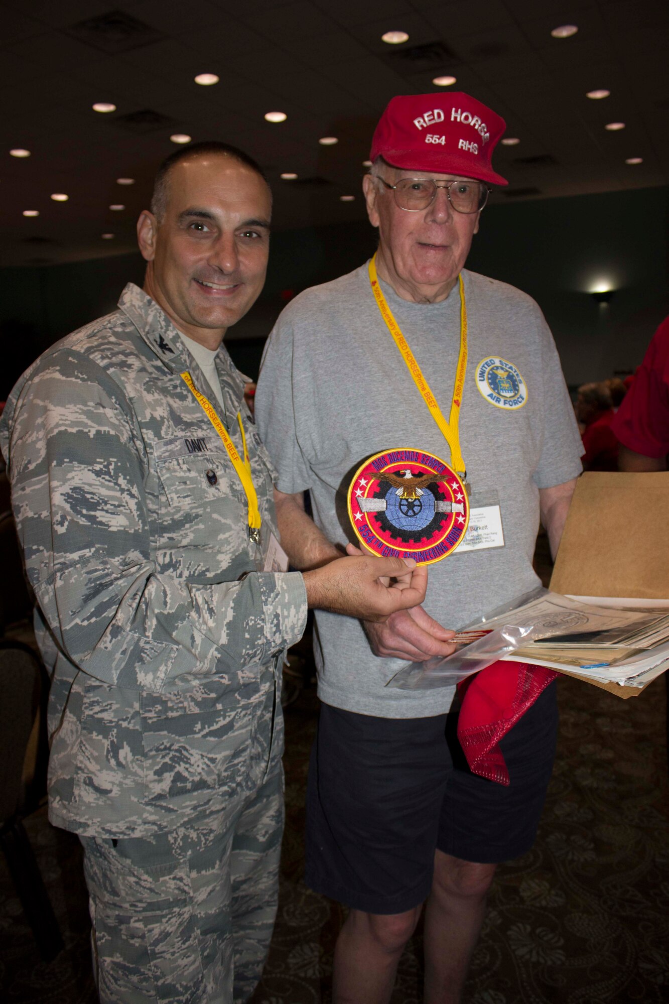 At right, John Burkett, original member of the 554th RED HORSE squadron, shares previous squadron patches with Col. Anthony Davit at the RED HORSE Association’s 50th anniversary convention in Fort Walton Beach, Florida.  (U.S. Air Force Photo/Mekka Parish/Released)