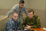 U.S. Navy Rear Adm. Brian Brown (seated left), Joint Functional Component Command for Space (JFCC Space) deputy commander, Royal Canadian Air Force (RCAF) Brig. Gen. Michel Lalumiere (seated right), RCAF Director General Space, and U.S. Air Force Maj. Daniel Rubalcaba, Rear Adm. Brownâ€™s executive officer, prepare for a battle update and assessment briefing, Nov. 3, 2015, at the Joint Space Operations Center, Vandenberg Air Force Base, Calif., in support of Exercise GLOBAL THUNDER 16. Allied participation in the exercise strengthens relationships with our international partners and provides additional levels of resiliency in our combined forces. GLOBAL THUNDER is an annual U.S. Strategic Command training event that assesses command and control functionality in all USSTRATCOM mission areas and affords component commands a venue to evaluate their joint operational readiness. Planning for GLOBAL THUNDER 16 has been under way for more than a year and is based on a notional scenario with fictitious adversaries. One of nine DoD unified combatant commands, USSTRATCOM has global strategic missions, assigned through the Unified Command Plan, which include strategic deterrence; space operations; cyberspace operations; joint electronic warfare; global strike; missile defense; intelligence, surveillance and reconnaissance; combating weapons of mass destruction; and analysis and targeting. (U.S. Air Force photo by Capt. Nicholas Mercurio/Released)
