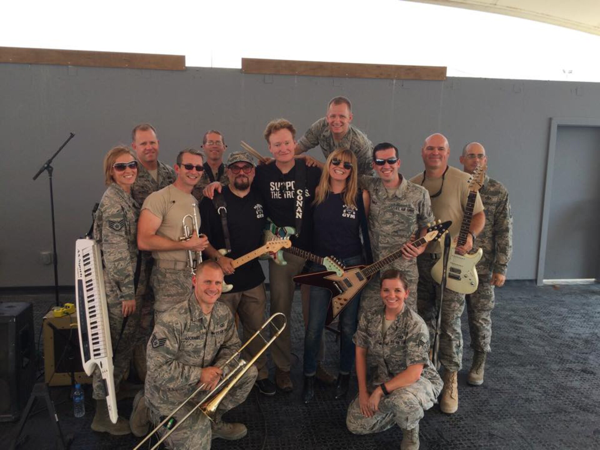 The U.S. Air Forces Central Command band poses for a photo with Conan O'Brien, Conan's house band leader Jimmy Vivino, and Grace Potter before an event at Al Udeid Air Base, Qatar, Nov. 3, 2015. The band served as the house band during the event as well as providing backup for Potter. (Courtesy Photo)