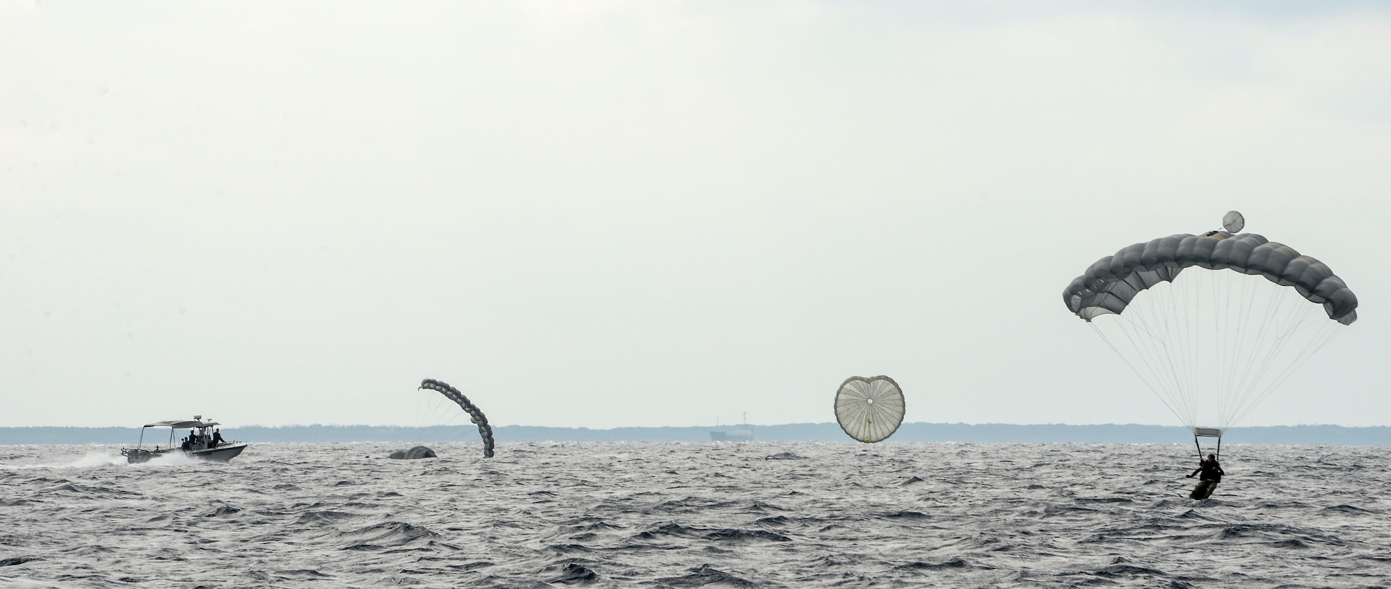 Airmen and equipment from Alaska Air National Guard’s 212th Rescue Squadron land on the ocean surface Oct. 31, 2015, near the coast of White Beach Naval Station, Okinawa, Japan. A guardian angel rescue team was delivered across the Pacific Ocean by a C-17 Globemaster to conduct long range search and rescue training with members from the 31st RS, Kadena Air Base, Japan. (U.S. Air Force photo/Senior Airman John Linzmeier)