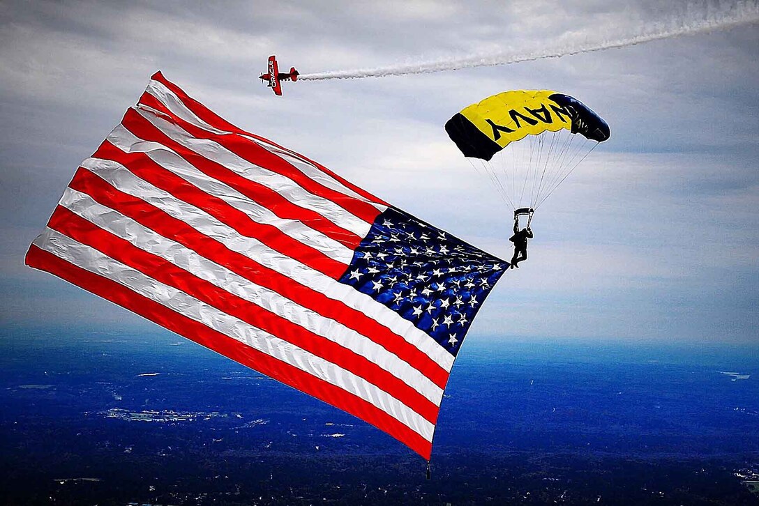 U.S. Navy Petty Officer 1st Class Trevor Thompson presents the American flag during a demonstration at The Great Georgia Air Show in Peachtree City, Ga., Oct. 31, 2015. The Navy Parachute Team performs aerial parachute demonstrations around the nation to support Naval Special Warfare and Navy recruiting. U.S. Navy photo by James Woods