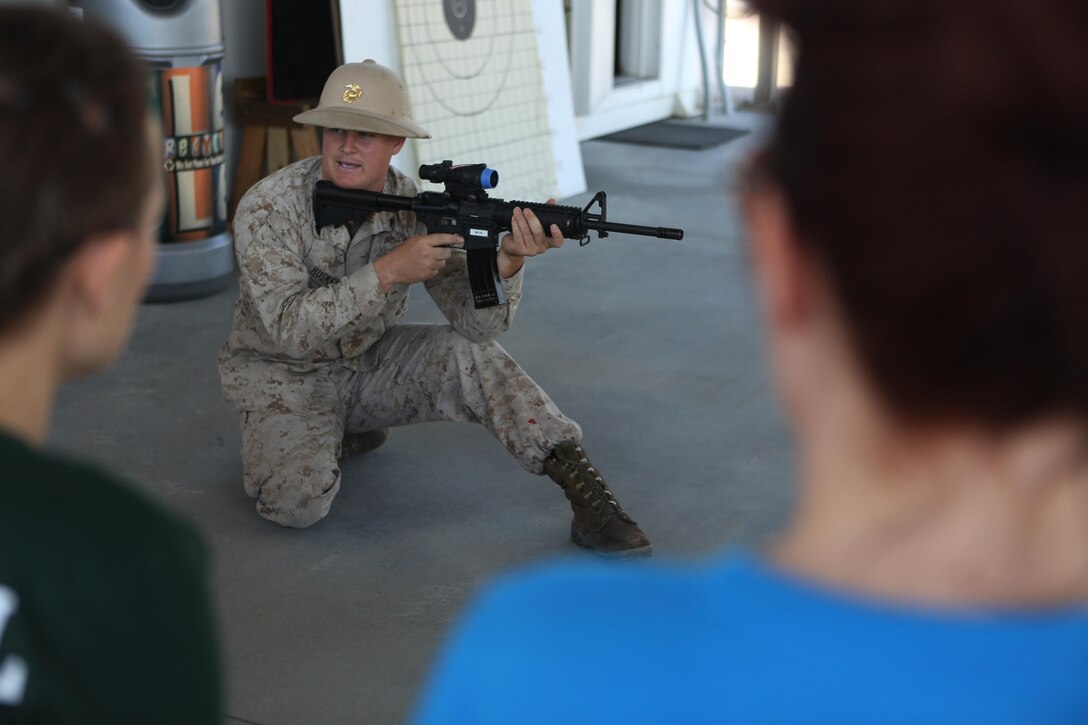 Cpl. Mitchell Huskey demonstrates firing positions during a weapons demonstration at Marine Wing Headquarters Squadron 2’s Warrior Day at Marine Corps Air Station Cherry Point, N.C., Oct.30, 2015. Marines with MWHS-2 hosted an interactive day where families could participate in some of the routine training their Marines undergo. Family members had the opportunity to fire in a simulated range, experience night vision equipment, partake in a combat fitness test, receive a Marine Corps Martial Arts Program class and brave the obstacle course.  Huskey is a marksmanship coach with Marine Aviation Logistics Squadron 14. (U.S. Marine Corps photo by Cpl. N.W. Huertas/ Released) 