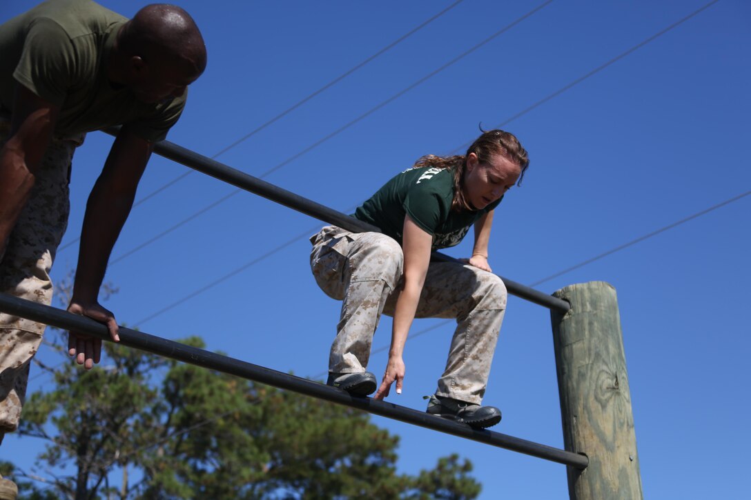 Antoinette Harrell is guided through an obstacle during the Marine Wing Headquarters Squadron 2’s Warrior Day at Marine Corps Air Station Cherry Point, N.C., Oct.30, 2015. Marines with MWHS-2 hosted an interactive day where families could participate in some of the routine training Marines undergo. Family members had the opportunity to fire in a simulated range, experience night vision equipment, partake in a Combat Fitness Test, receive a Marine Corps Martial Arts Program class and brave the obstacle course. Harrell is the spouse of Lt. Col. Andre Harrell, an aviation supply officer with the squadron. (U.S. Marine Corps photo by Cpl. N.W. Huertas/ Released)