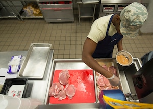 U.S. Air Force Senior Airman Fritz Javel, 633rd Force Support Squadron services journeyman seasons pork chops in the Raptor Café at Langley Air Force Base, Va. Oct. 30, 2015. Javel has been a services journeyman for three years. (U.S. Air Force photo by Staff Sgt. John D. Strong II/Released)