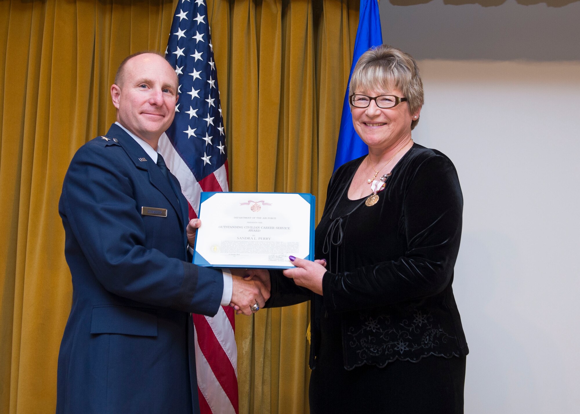 Brig. Gen. Carl Schaefer, 412th Test Wing commander, presents Sandra Perry with the Air Force Outstanding Civilian Career Service Award at Club Muroc, Oct. 30. Perry retired after 30 years of federal service. Her last position was as 412th Test Wing Financial Management director. (U.S. Air Force photo by Ethan Wagner)