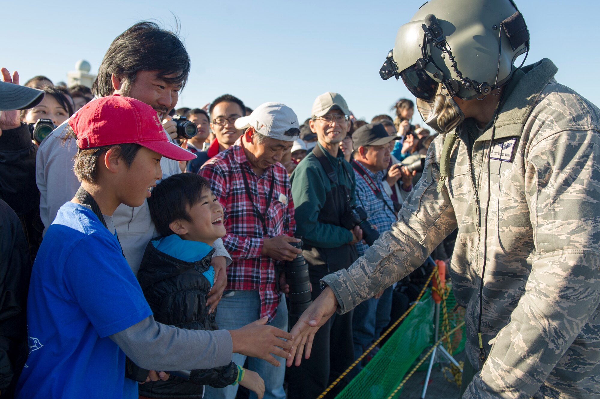 Tech. Sgt.  Michael Wright, 459th Airlift Squadron UH-1N Huey flight engineer, shakes hand with a child at Iruma Air Base, Japan, Nov. 3, 2015. The 459th Airlift Squadron’s participation in the annual air show allowed Yokota Airmen an opportunity to build relationships with their Japan Air Self-Defense Force partners and interact with the members of the local community. (U.S. Air Force photo by Airman 1st Class Delano Scott/Released)