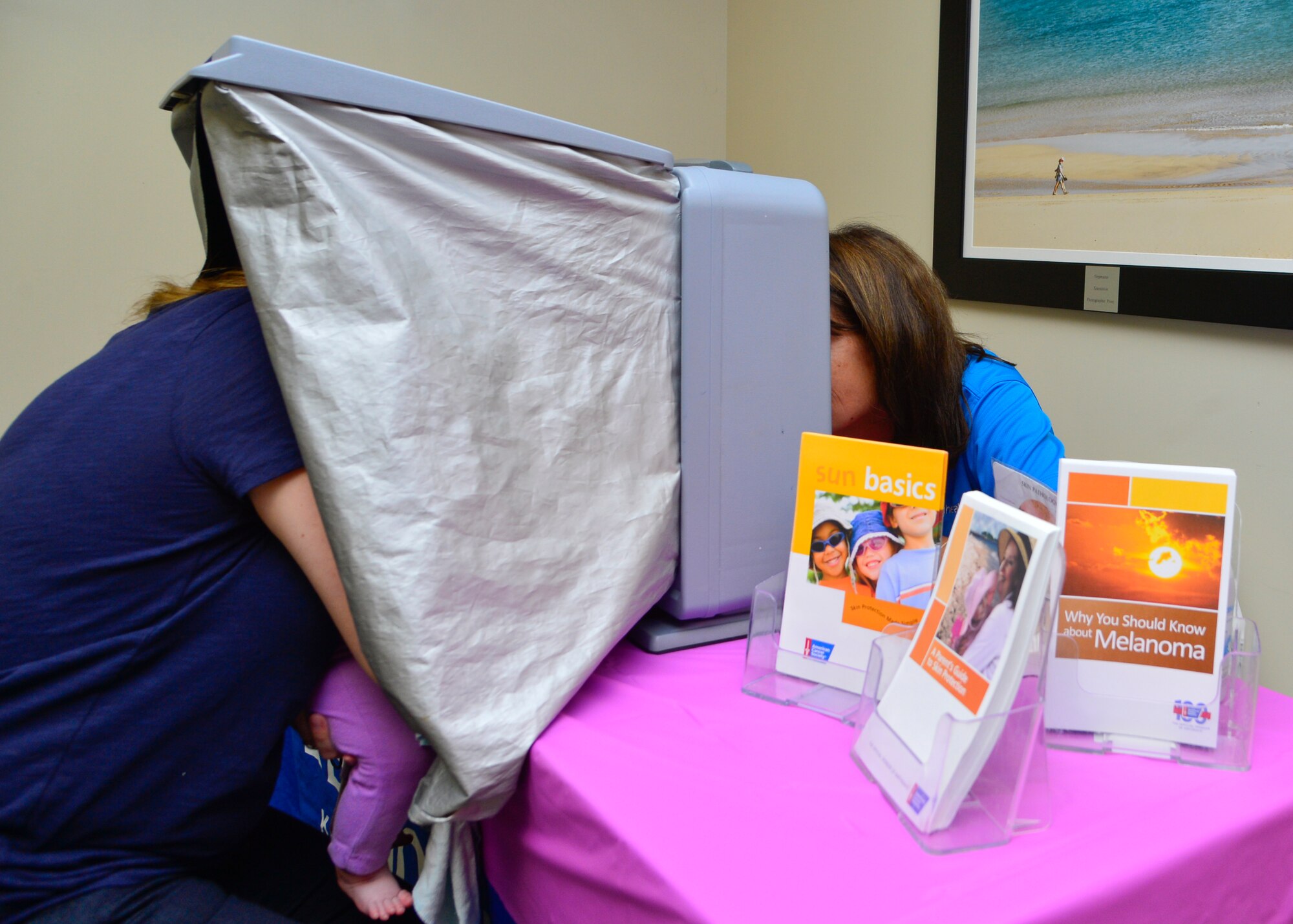 Ashley Childs, wife of Airman 1st Class Brady Childs, 9th Airlift Squadron loadmaster, and her daughter, left, receive a free facial skin cancer screening at the Woman’s Health Event Oct. 30, 2015, at the 436th Medical Group Clinic on Dover Air Force Base, Del. Bayhealth Kent General provided free screenings by looking at patients’ faces under black lights and looked for sun damage spots that could potentially be cancerous. (U.S. Air Force photo/Senior Airman William Johnson)