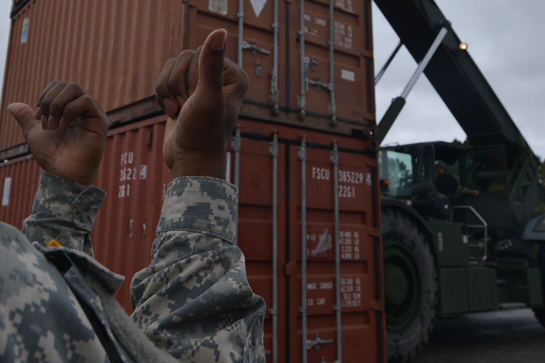 U.S. Army Pfc. Richard Jones, Maritime and Intermodal Training School student, guides a rough terrain container handler operator for the course at Fort Eustis, Va., Oct. 28, 2015. During the course, the students, who all hold various cargo specialties, learn how to direct and operate the handlers which can move 20 and 40 foot containers, carrying essential supplies. (U.S. Air Force photo by Staff Sgt. Natasha Stannard/ Released)