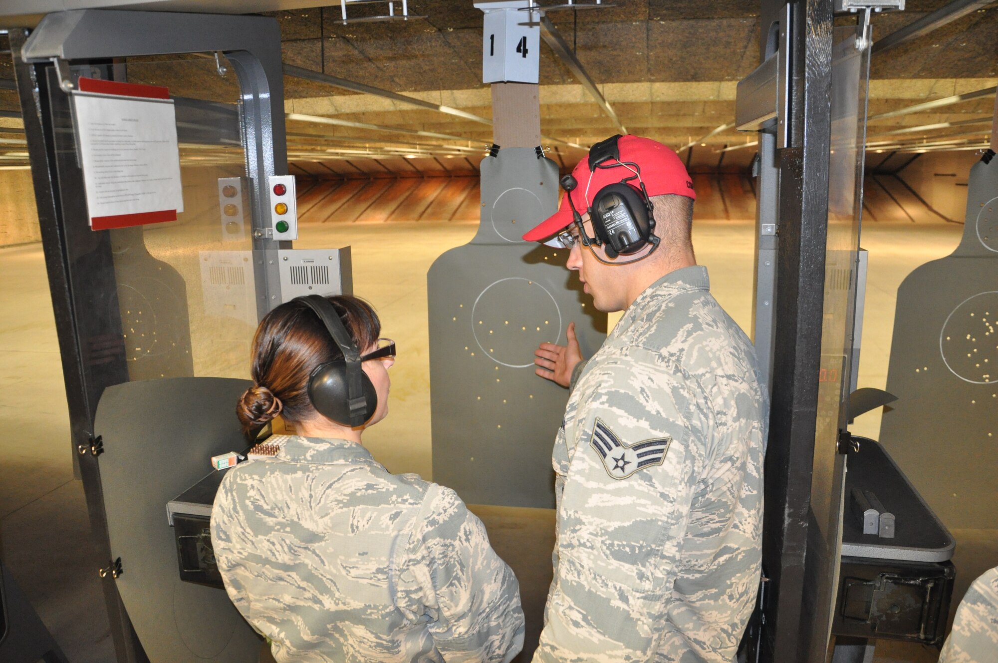 Senior Airman Daniel Conrad, 88th Security Forces Squadron CATM instructor, reviews an M9 qualifications course student’s target with her. (U.S. Air Force photo/Bryan Ripple.)