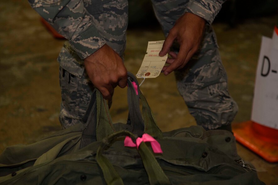 A 35th Fighter Wing Airman readies his chemical bag while passing through the personnel deployment function line at Misawa Air Base, Japan, Nov. 2, 2015. More than 300 Airmen were processed through the PDF in support of exercise Vigilant Ace 16, with many bringing overnight bags, medical records and mission oriented protective posture gear to their final destination of Osan Air Base, Korea. (U.S. Air Force photo by Airman 1st Class Jordyn Fetter/Released) 