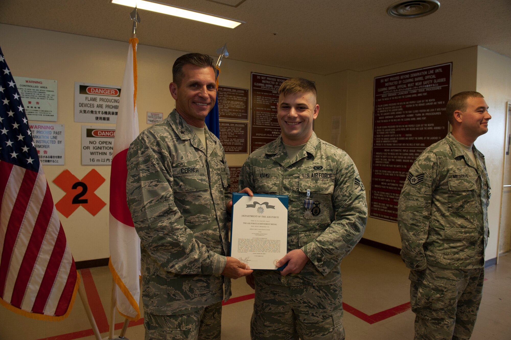 U.S. Air Force Brig. Gen. Barry Cornish, 18th Wing commander, presents Airman 1st Class Ethan Adams, 18th Security Forces Squadron response force member, with a certificate to accompany the Air Force Achievement Medal Nov. 4, 2015, at Kadena Air Base, Japan.  Adams was recognized for saving the life of an Airman who attempted suicide. (U.S. Air Force photo by Airman 1st Class Lynette M. Rolen)