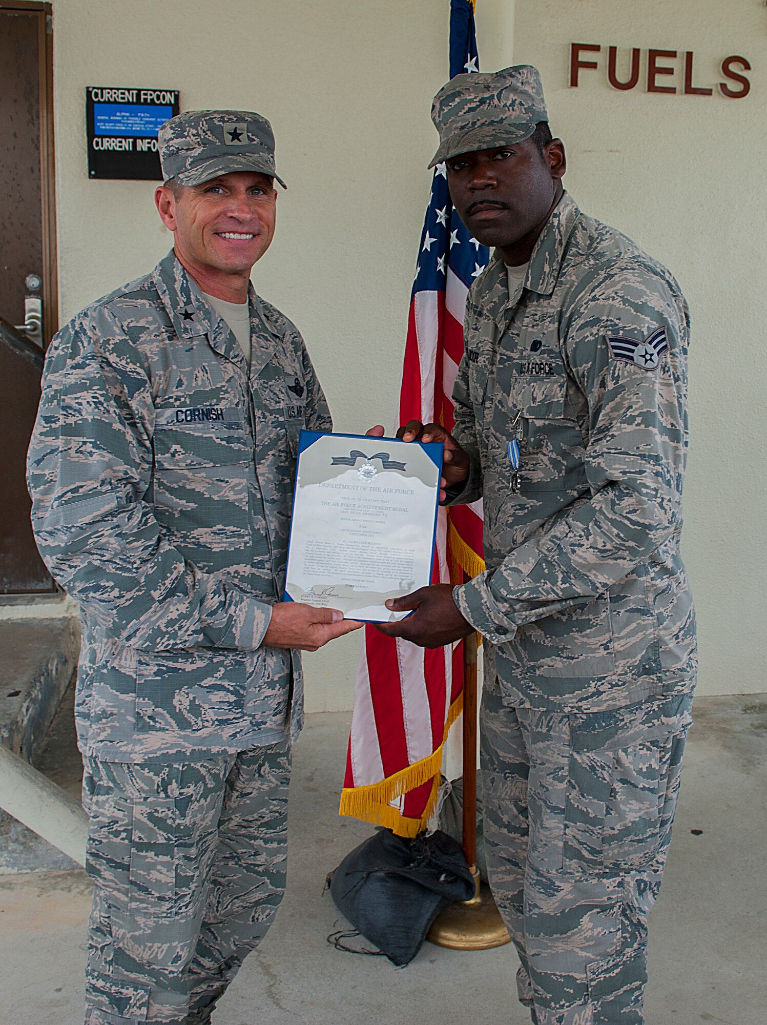 U.S. Air Force Brig. Gen. Barry Cornish, 18th Wing commander, hands Senior Airman Brian Moore, 18th Logistics Readiness Squadron fuels fixed facilities operator, an Air Force Achievement Medal citation Nov. 4, 2015, at Kadena Air Base, Japan. Moore and two other Airmen received the award for their role in saving the life of a fellow Airman. (U.S. Air Force photo by Airman 1st Class Corey M. Pettis)