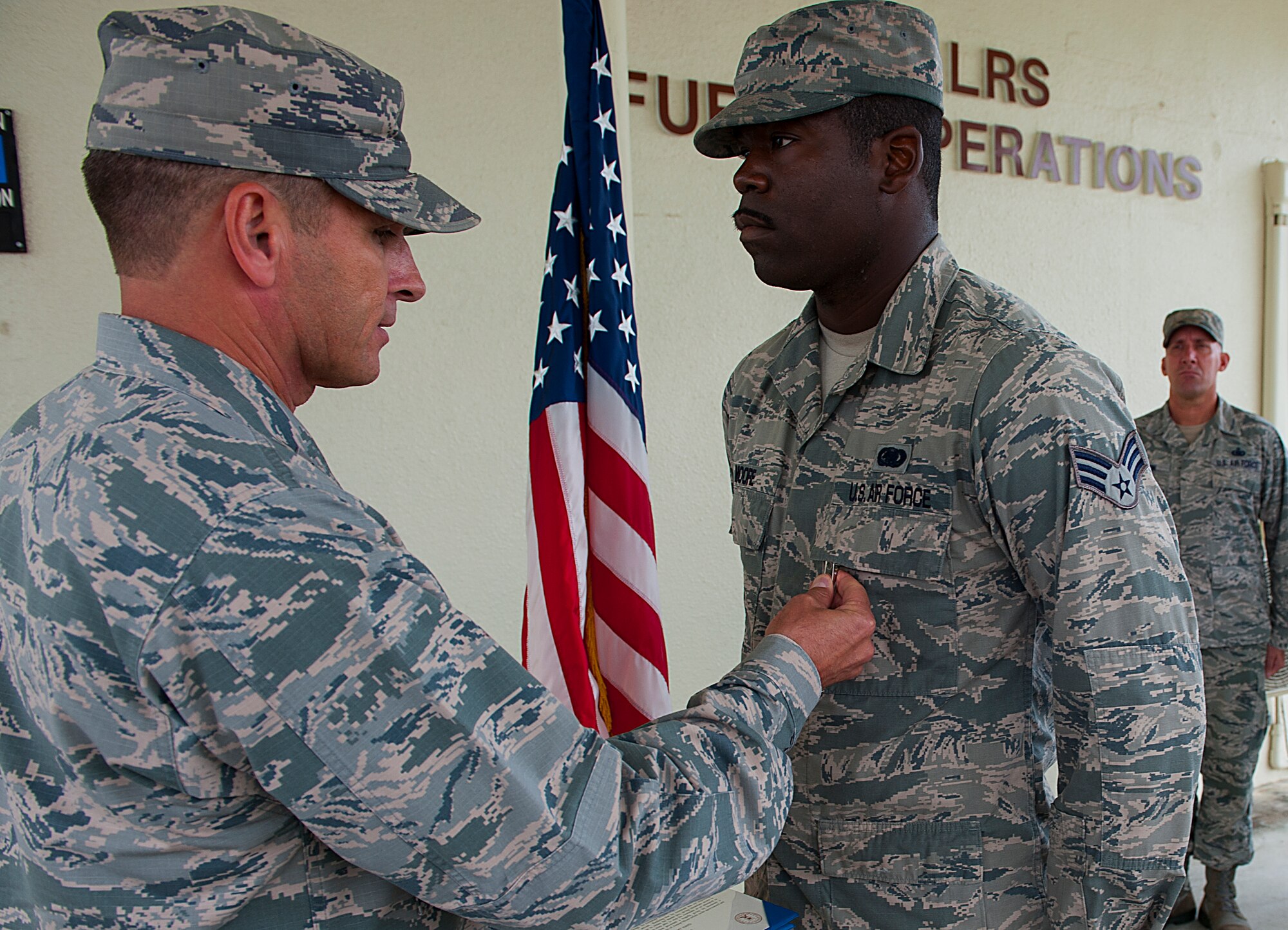 U.S. Air Force Brig. Gen. Barry Cornish, 18th Wing commander, pins the Air Force Achievement Medal on Senior Airman Brian Moore, 18th Logistics Readiness Squadron fuels fixed facilities operator, Nov. 4, 2015, at Kadena Air Base, Japan. Moore was instrumental in saving the life of a fellow Airman, who was attempting suicide. (U.S. Air Force photo by Airman 1st Class Corey M. Pettis)