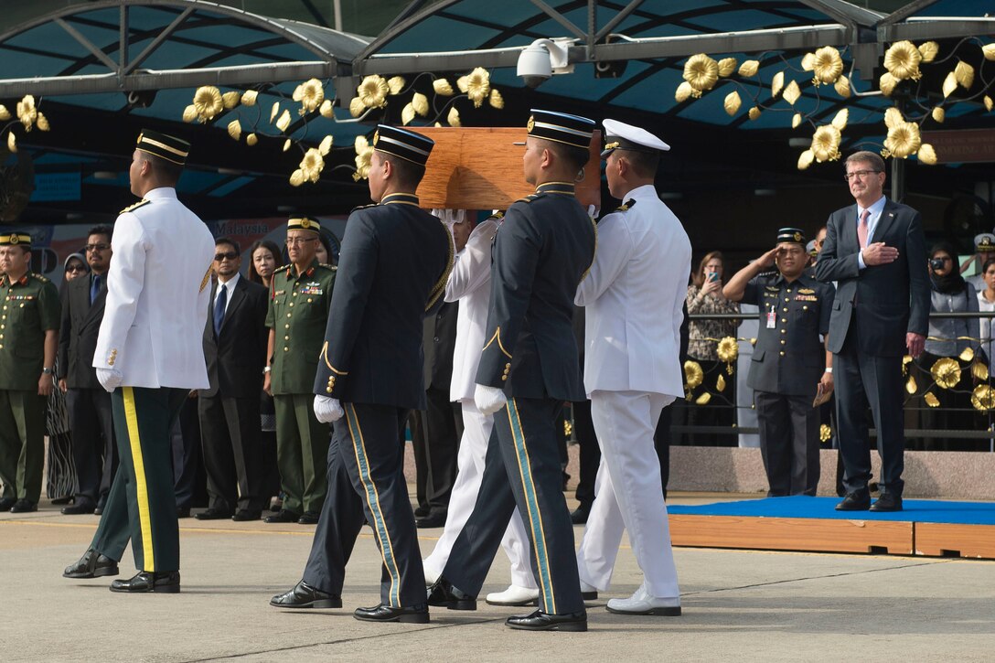U.S. Defense Secretary Ash Carter renders honors as a Malaysian military carry team transfers the remains of a recovered American World War II era aircrew to an American carry team during a repatriation ceremony in Subang, Malaysia, Nov. 5, 2015.  DoD photo by Air Force Senior Master Sgt. Adrian Cadiz