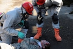 Citizen-Soldiers of the New York Army National Guard's 1156th Engineer Company in full hazardous material gear assist a civilian participant in Kingston, N.Y., during the extraction phase of a joint force first responders exercise in reaction to a radioactive attack. New York National Guard Citizen-Soldiers and -Airmen collaborate with local authorities to help train for the response to a radioactive terrorist attack, Nov. 5, 2011.