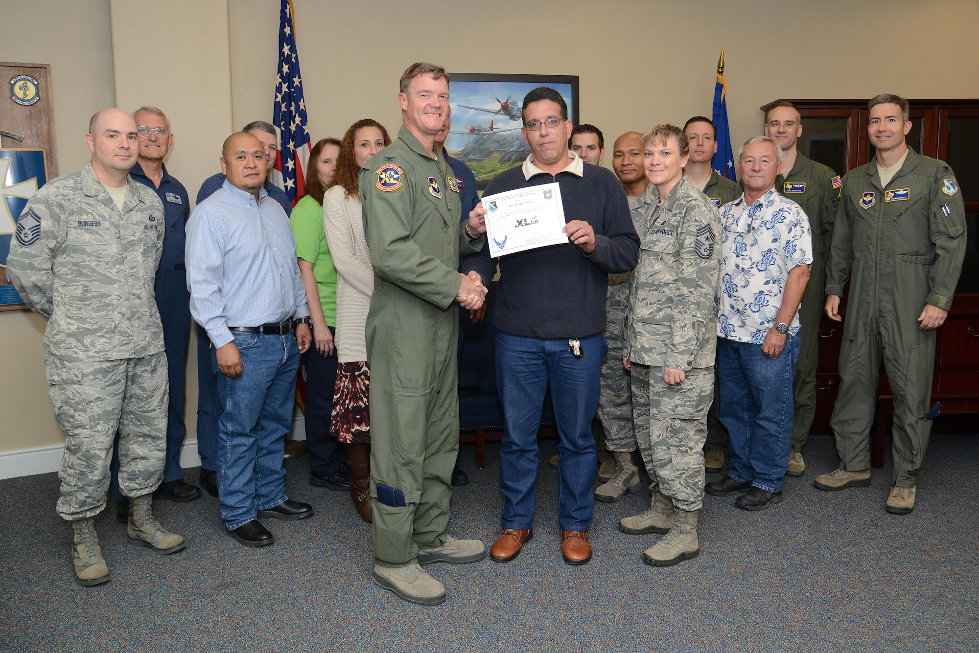 Joseph Pagan, center, 47th Operations Group quality assurance chief and building custodian, poses with Col. Thomas Shank, 47th Flying Training Wing commander, Chief Master Sgt. Teresa Clapper, 47th FTW command chief, after accepting the “XLer of the Week” award, here, Nov. 4, 2015. The “XLer” is a weekly award chosen by wing leadership and is presented to those who consistently make outstanding contributions to their unit and Laughlin. (U.S. Air Force photo by Airman 1st Class Ariel D. Partlow) (Released)