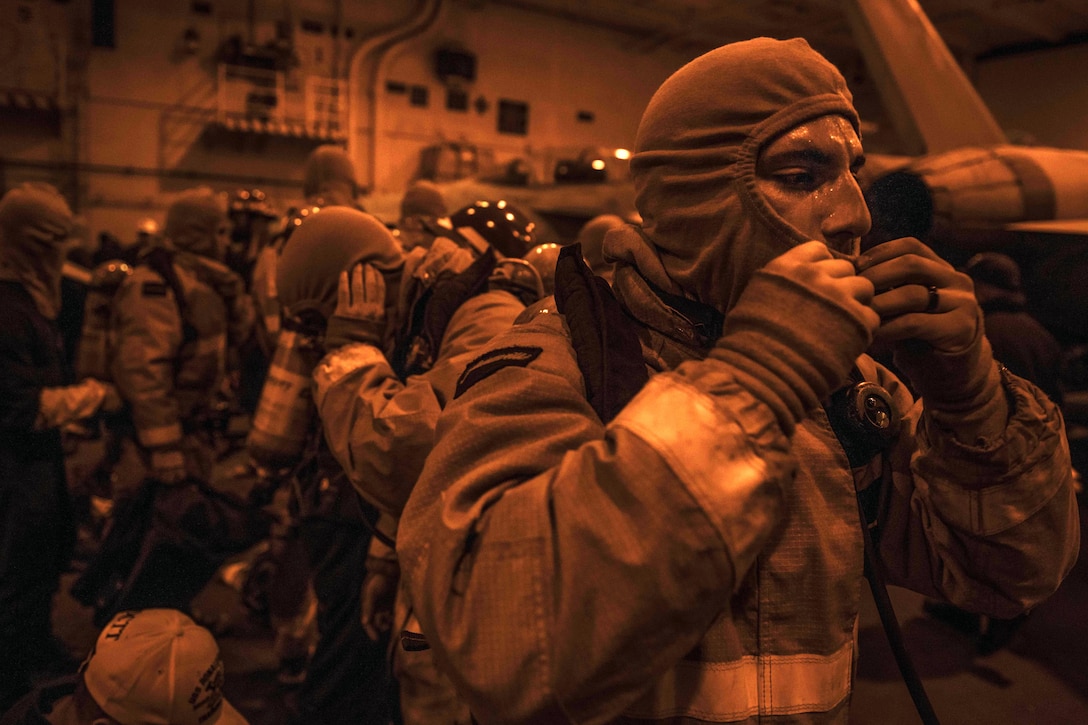 U.S. Navy Seaman Joseph Tribuzio dons his firefighting ensemble during a general quarters drill aboard the USS Ronald Reagan in the East China Sea, Nov. 5, 2015. U.S. Navy photo by Petty Officer 3rd Class Ryan McFarlane