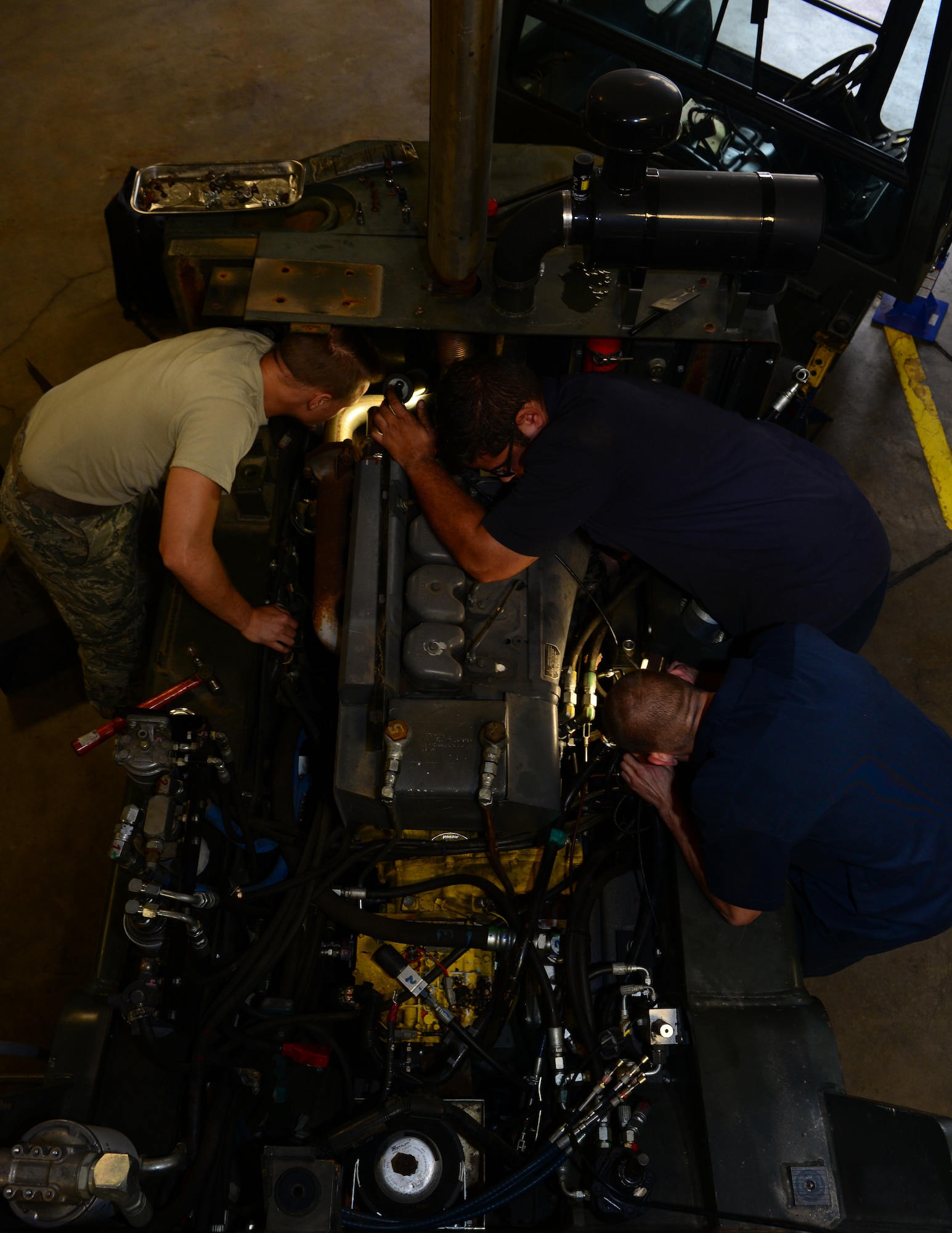 Senior Airmen Tyler Henderson, left, Brian Rodriguez, middle, and Trent Wischoff, 2nd Logistics Readiness Squadron vehicle maintainers, search for a leak inside a forklift at Barksdale Air Force Base, La., Nov. 2, 2015. From forklifts to buses to augers, 2nd LRS vehicle maintainers must fix the problem and supply vehicles units depend on for the mission. (U.S. Air Force photo/Airman 1st Class Luke Hill)