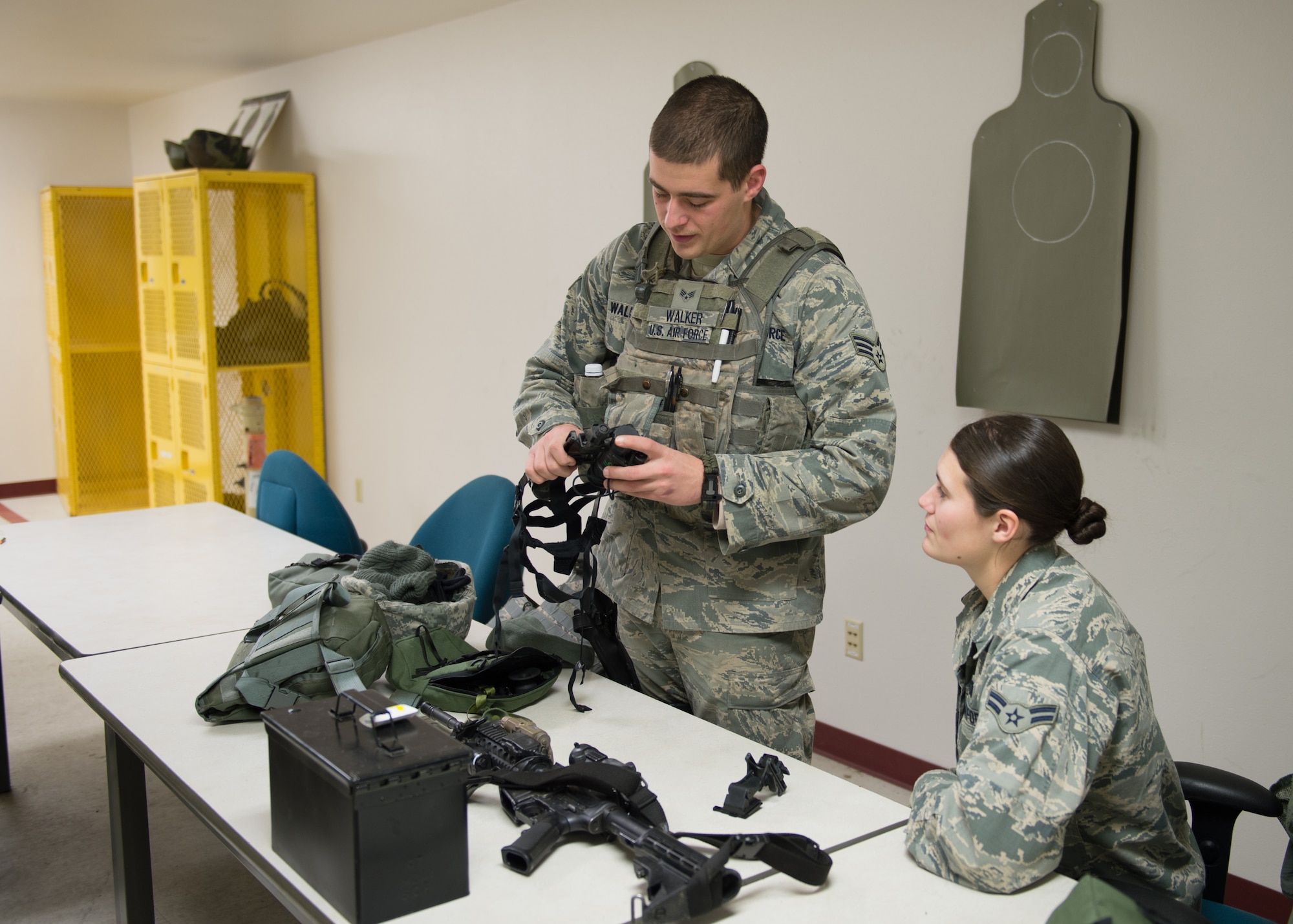 Senior Airman Brian Walker, a 354th Security Forces Squadron response force member, gives instructions on how to adjust the fit of night vision goggles (NVGs) to Airman 1st Class Hannah Janicki, Nov. 4, 2015, at the Eielson Air Force Base, Alaska, combat arms training range. A group of eight Airmen from the squadron used NVGs, tracer rounds, flashlights and laser sights to qualify on low-light shooting. (U.S. Air Force photo by Staff Sgt. Shawn Nickel/Released)