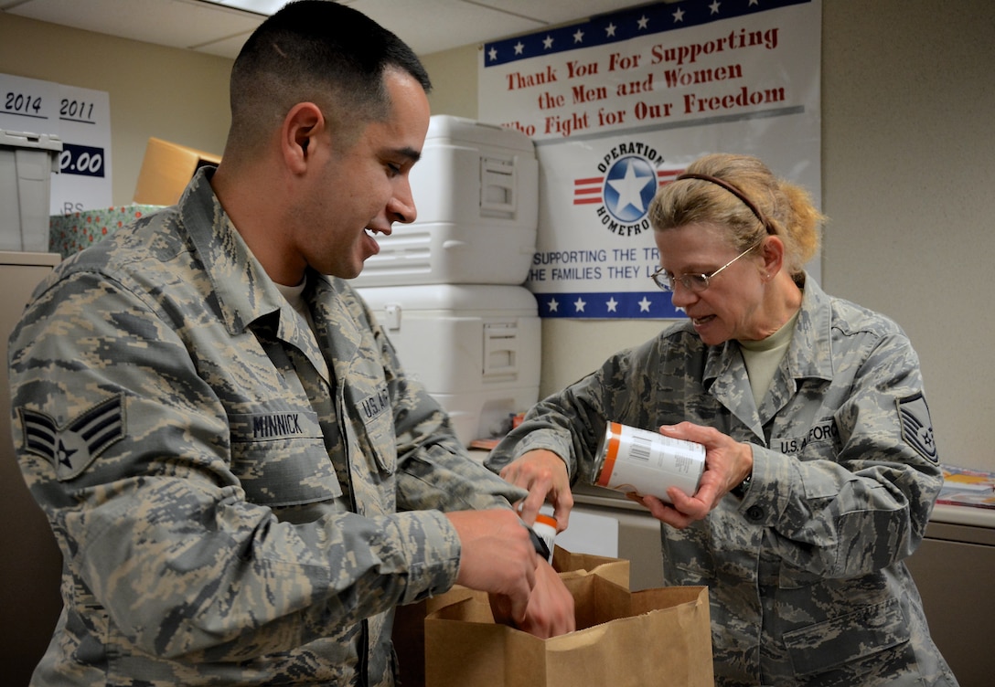 Senior Airman Jesse Minnick and Master Sgt. Deb Teague filled holiday meal baskets at the 932nd Airlift Wing Airman & Family Readiness Center at Scott Air Force Base, Illinois. Teague and her team gathered donations of non-perishable food items and gift cards that were used to build the holiday meal baskets. The baskets, which provide everything needed to prepare a home-cooked meal, will be distributed to families who could use a little extra support during the holiday season. (U.S. Air Force photo by Tech. Sgt. Jodi Ames)