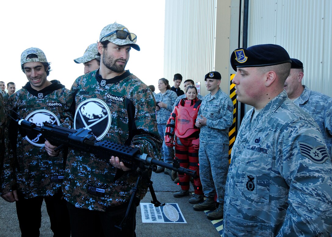 Staff Sgt. Kevin Dash, Security Forces member, 914th Security Forces Squadron explains the capabilities of some of the weapons that are used by the Air Force Reserve to Zach Bogosian, player for the Buffalo Sabres while team members Matt Moulson and Zemgus Girgensons look on at the Niagara Falls Air Reserve Station, N.Y. on November 4, 2015. Some members of the NHL team visited the base to thank the veterans for their service and also included a tour of the aircraft and various other interactive displays designed to educate on the 914th mission capabilities. (U.S. Air Force photo by Peter Borys)