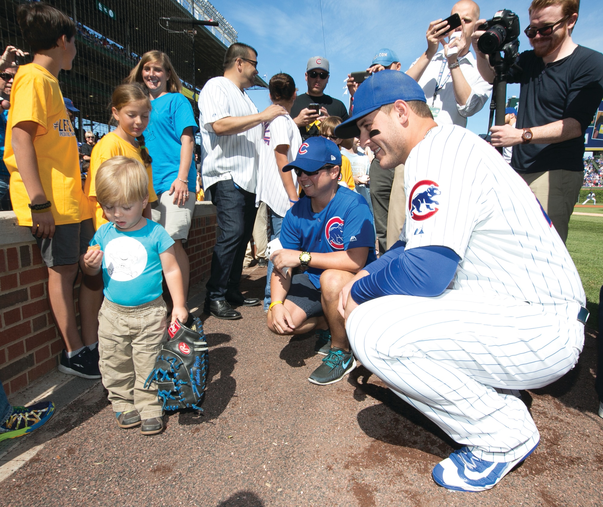 Julian Leonard, 2, holds a snack and Cubs first baseman Anthony Rizzo’s glove as Rizzo, far right, looks on at Wrigley Field in September. Back from far left, Julian’s brother, Jayden, sister, Sofie, and mother, Jessica, stand behind him. (Courtesy photo)