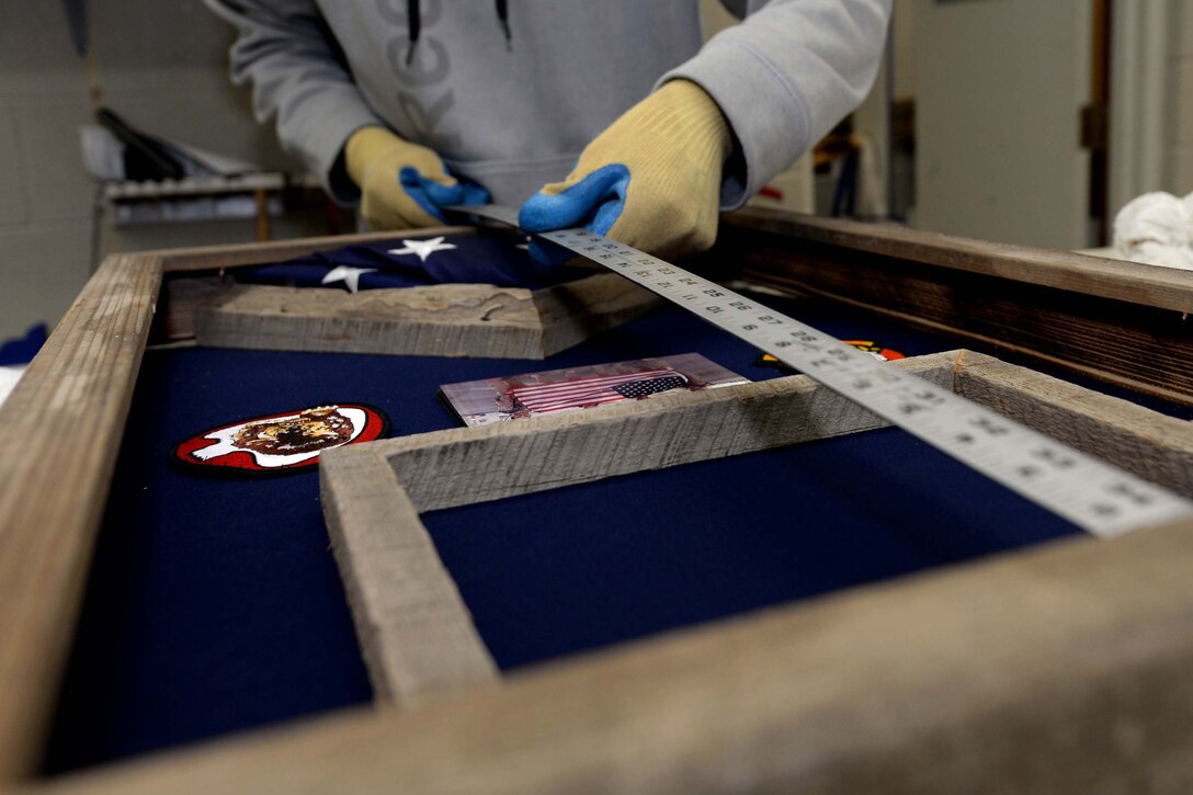 Joe Altergott, 28th Force Support Squadron visual information specialist, measures the height of a shadowbox at Ellsworth Air Force Base, S.D., Oct. 23, 2015. The box contains items flown by the 37th Bomb Squadron during missions in support of Operation Inherent Resolve on the 100th birthday of retired Lt. Col. Dick Cole, one of two surviving Doolittle Raiders. (U.S. Air Force photo by Senior Airman Rebecca Imwalle/Released)