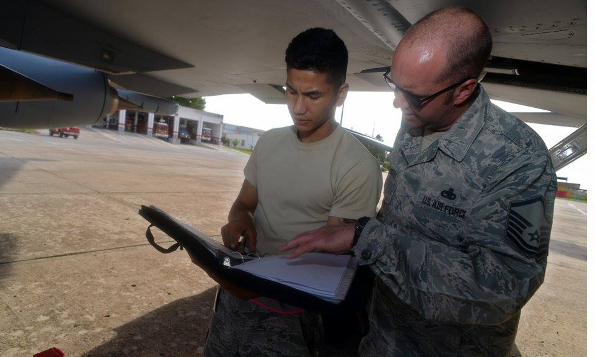 U.S. Air Force Staff Sgt. Wilvan Tan, left, 100th Aircraft Maintenance Squadron electrical environmental technician and U.S. Air Force Master Sgt. Brian Flanders, 100th AMXS production superintendent, look through KC-135 Stratotanker maintenance forms Oct. 29, 2015, at Son San Juan Air Base, Spain. Tan was replacing a gear-retraction piece. (U.S. Air Force photo by Senior Airman Christine Halan/Released)