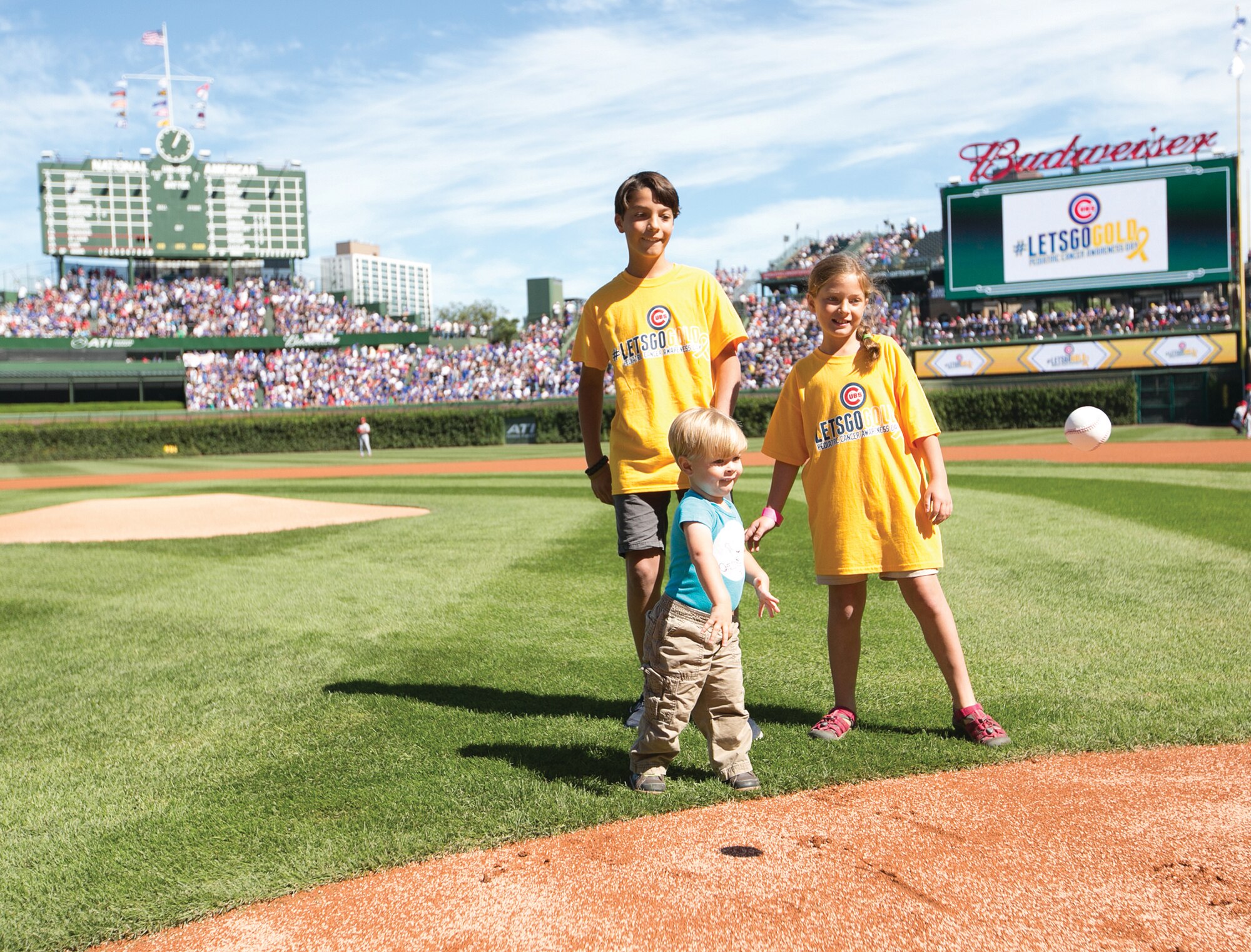 Julian Leonard, front left, throws the ceremonial first pitch at a Cubs baseball game as his brother, Jayden, and sister, Sofie, watch in September at Wrigley Field in Chicago. (Courtesy photo)