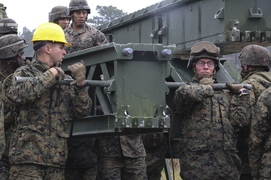 Marine students in the 8th Engineer Support Battalion Bridge Master’s Course lift a bridge bay during a field exercise at Camp Lejeune, N.C., Nov. 4, 2015. Marines were required to work together to lift weight between 400 and 600 pounds to build a bridge that covered an 82-foot gap. (U.S. Marine Corps photo by Cpl. Paul S. Martinez/Released)
