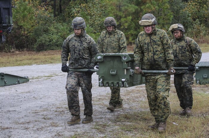 Marine students in the 8th Engineer Support Battalion Bridge Master’s Course lift a bridge bay during a field exercise at Camp Lejeune, N.C., Nov. 4, 2015. The course teaches Marines to lead the bridge building process, and is hosting Marines from 9th Engineer Support Battalion, 3rd Marine Logistics Group, based in Camp Hansen, Okinawa. During the exercise, Marines constructed and deconstructed a bridge 11 bays in length. (U.S. Marine Corps photo by Cpl. Paul S. Martinez/Released)