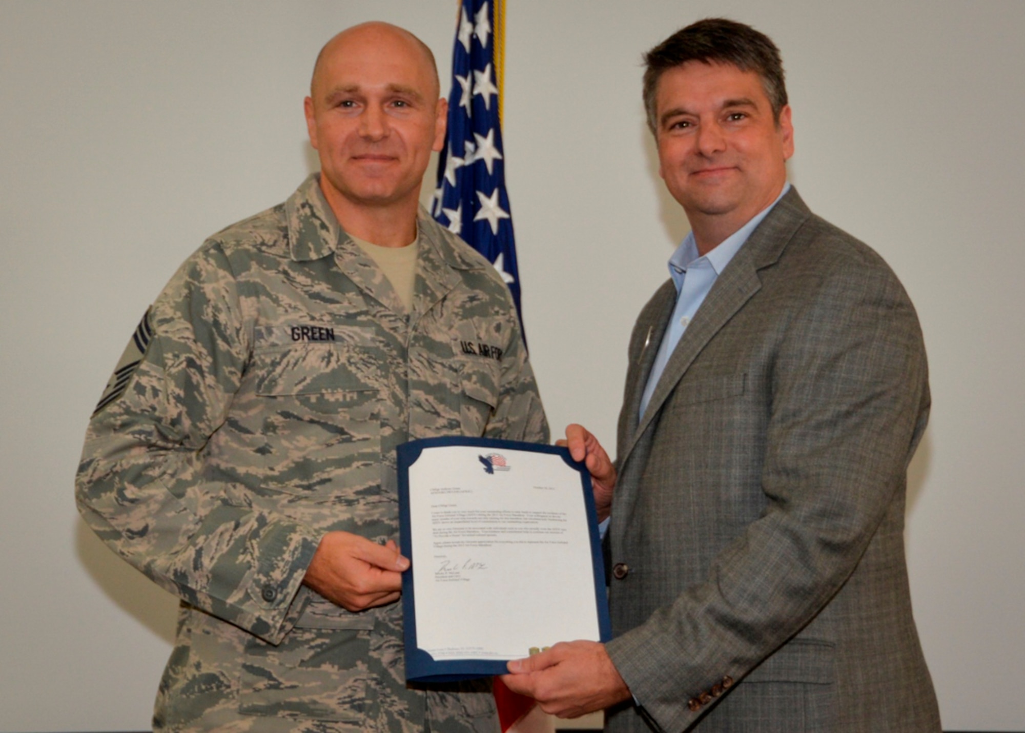 Chief Master Sgt. Anthony Green, Air Force Special Operations Air Warfare Center, receives a letter of appreciation from Ret. Chief Master Sgt. Scott Delveau, Director of Development for the Air Force Enlisted Village, during an AFSOAWC awards ceremony Oct. 29  at Duke Field, Fla.   Green raised $500 to benefit the AFEV by running the Air Force Marathon, Sept. 19 at the National Museum of the U.S. Air Force in Ohio.  AFEV is a non-profit organization that provides safe, secure and dignified homes for surviving spouses of retired Air Force personnel.  (Courtesy photo)
