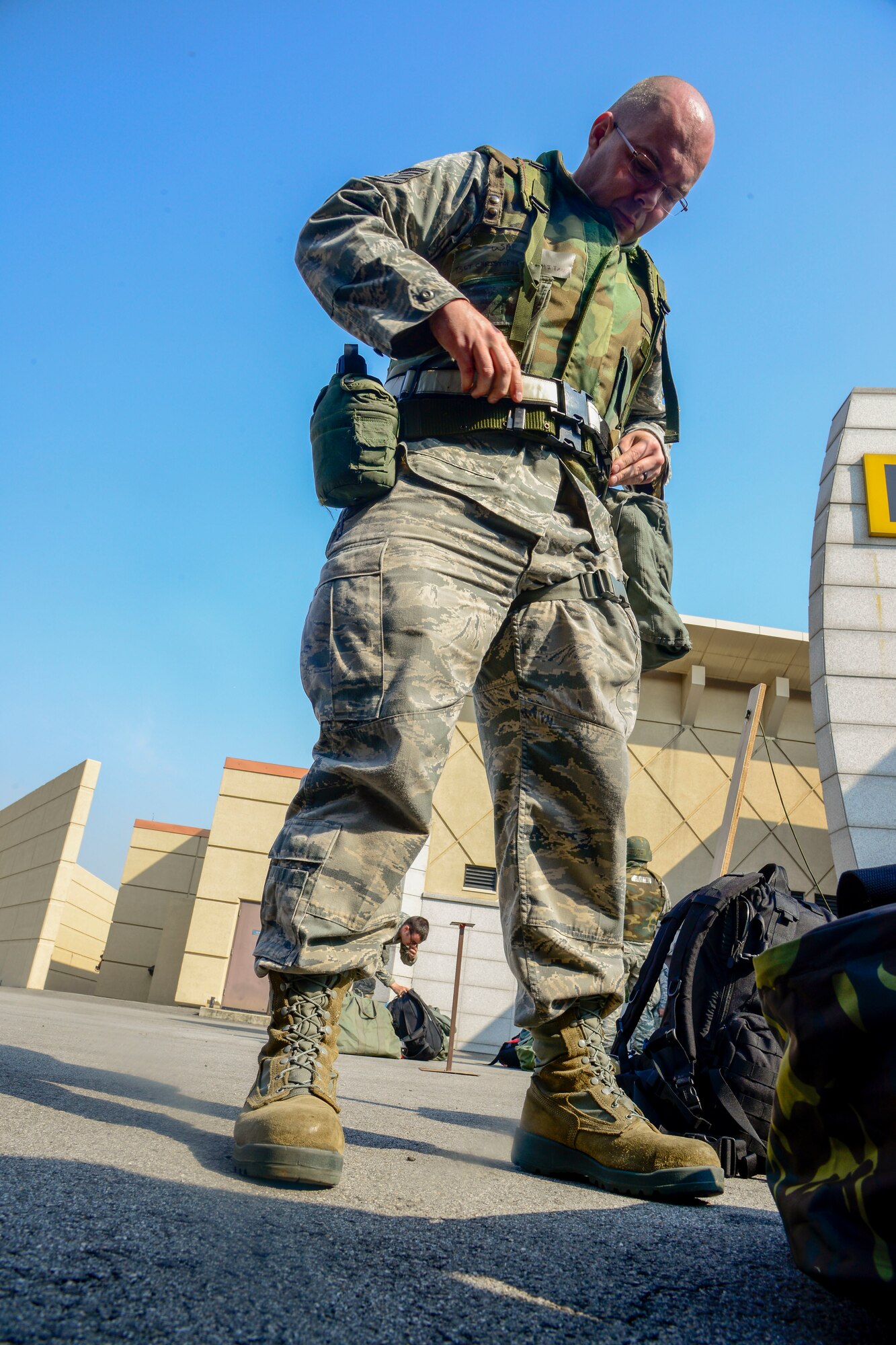 Tech Sgt. Christopher Whitmore, 35th Maintenance Squadron aircrew egress systems craftsmen, adjusts his protective equipment after inprocessing at the passenger terminal during the Vigilant Ace 16 exercise on Osan Air Base, Republic of Korea, Nov. 2, 2015. Whitmore along with more than 1,000 Air Force and Marine personnel deployed to the peninsula to play in the annual exercise formerly known as Beverly Bulldog. (U.S. Air Force photo/Senior Airman Kristin High)