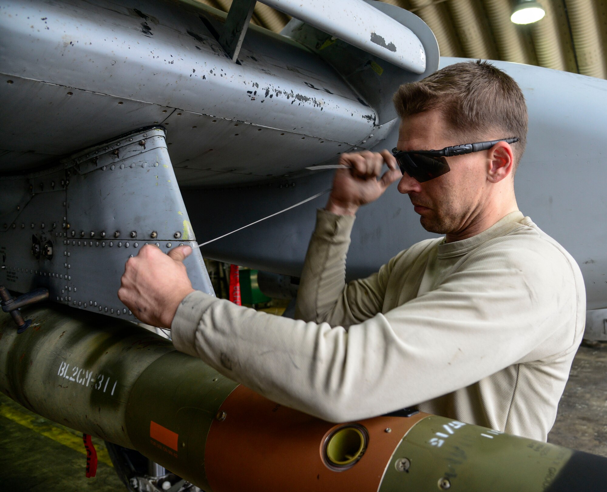 Staff Sgt. Christopher Uecker, 25th Aircraft Maintenance Unit weapons load crew team chief, tightens arming wire on an A-10 Thunderbolt II during the Vigilant Ace 16 exercise on Osan Air Base, Republic of Korea, Nov. 1, 2015. The arming wire holds the guided bomb unit in place until proper aerial release. (U.S. Air Force photo/Senior Airman Kristin High)