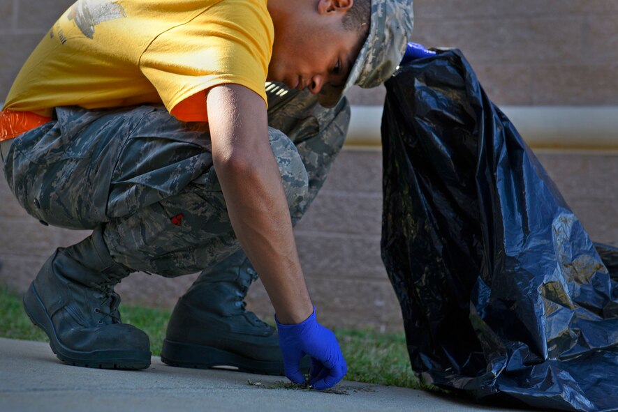 U.S. Air Force Airman Darius Moss, 20th Aircraft Maintenance Squadron tactical aircraft maintainer, clears weeds off a sidewalk during a dorm cleanup event at Shaw Air Force Base, S.C., Oct. 30, 2015.  Airmen cleaned the interior and exterior of their dormitories with the assistance of their supervisors.  (U.S Air Force photo by Airman 1st Class Christopher Maldonado)