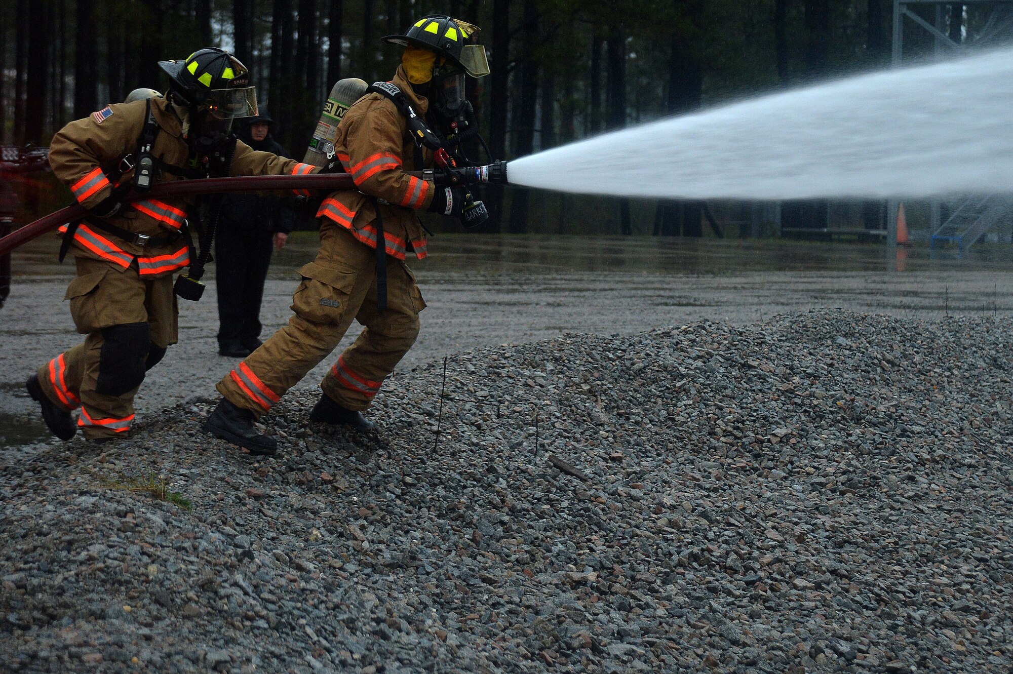 Two U.S. Airmen with the 20th Civil Engineer Squadron, move closer to put out a fire during operational readiness exercise Weasel Victory 16-02 at Shaw Air Force Base, S.C., Nov. 4, 2015. An ORE tests the combat capabilities and readiness of the 20th Fighter Wing through a variety of simulated events. (U.S. Air Force photo by Senior Airman Michael Cossaboom)