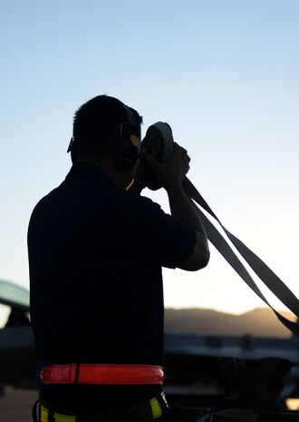 Staff Sgt. Won Yi, Tomahawk Aircraft Maintanence Unit weapons load crew team chief, rolls up tie-down straps during a quarterly weapons load crew competition on Nellis Air Force Base, Nev., Oct. 23, 2015. Weapons load teams are evaluated on their ability to properly follow all checklists, technical orders and safety procedures. (U.S. Air Force photo by Airman 1st Class Rachel Loftis)