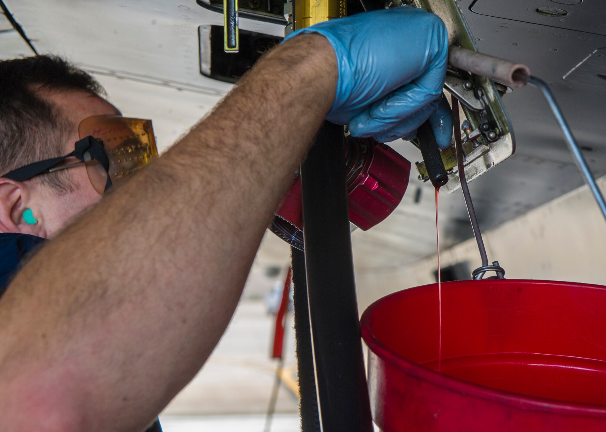 Staff Sgt. Nathaniel Gladney, a dedicated crew chief with the 54th Aircraft Maintenance Squadron at Holloman, drains hydraulic fluid from an F-16 Fighting Falcon on Nov. 4. Aircraft purification is the process to remove water, air and contaminant particles from the hydraulic fluid in an aircraft. Holloman Airmen performed aircraft purification for the first time on an F-16 on Nov.3. (U.S. Air Force photo by Airman 1st Class Emily A. Kenney/Released)