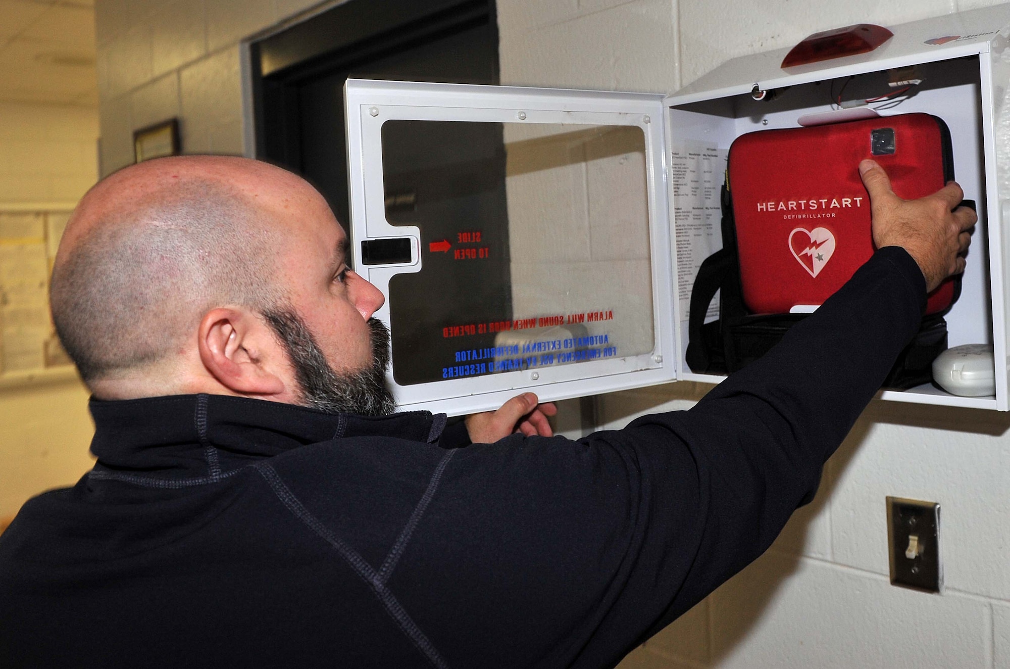Scott Peavy, Fitness Program coordinator, retrieves an Automated External Defibrillator from its casing in the lobby of the Base Fitness Center. (U.S. Air Force photo by Tommie Horton)